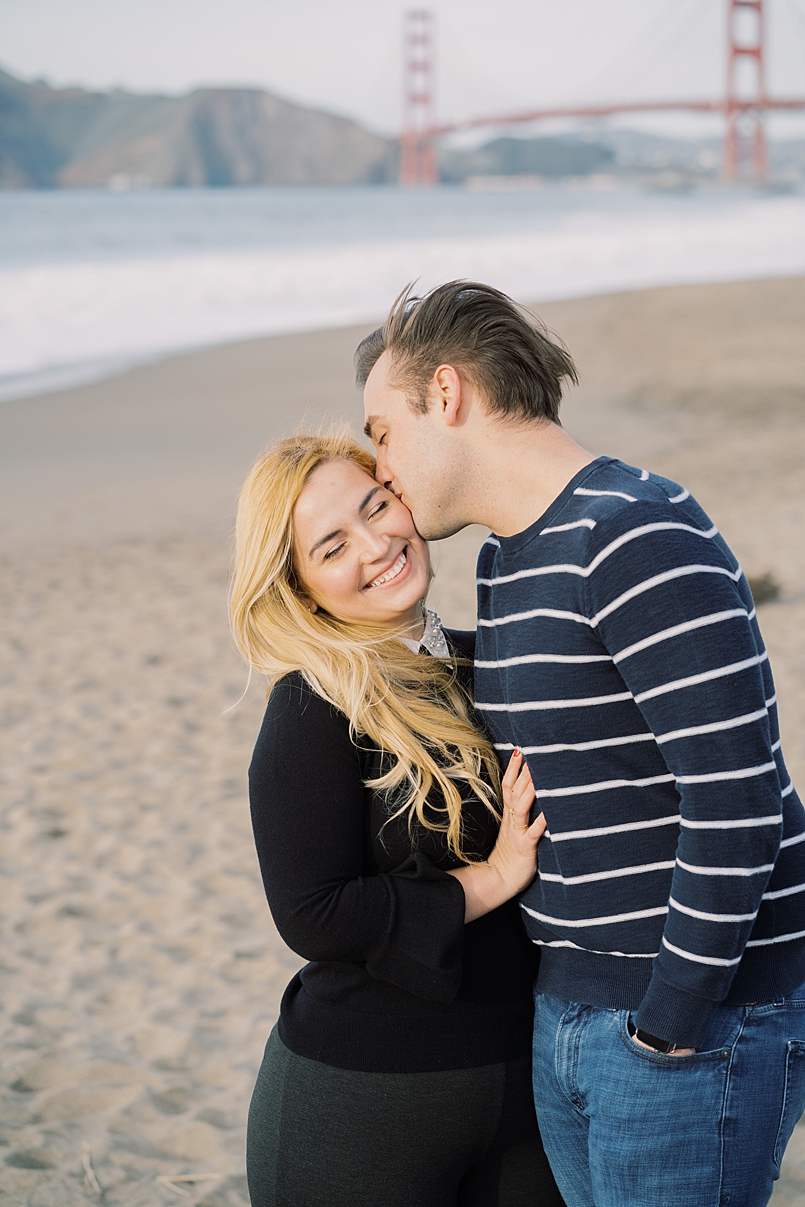 man kissing woman on the cheek on baker beach