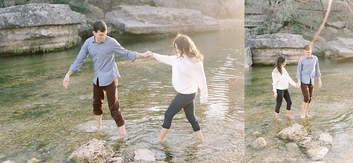 A happy, attractive couple hold hands while walking barefoot through the Colorado River in Bull Creek Park, Austin, Texas.
