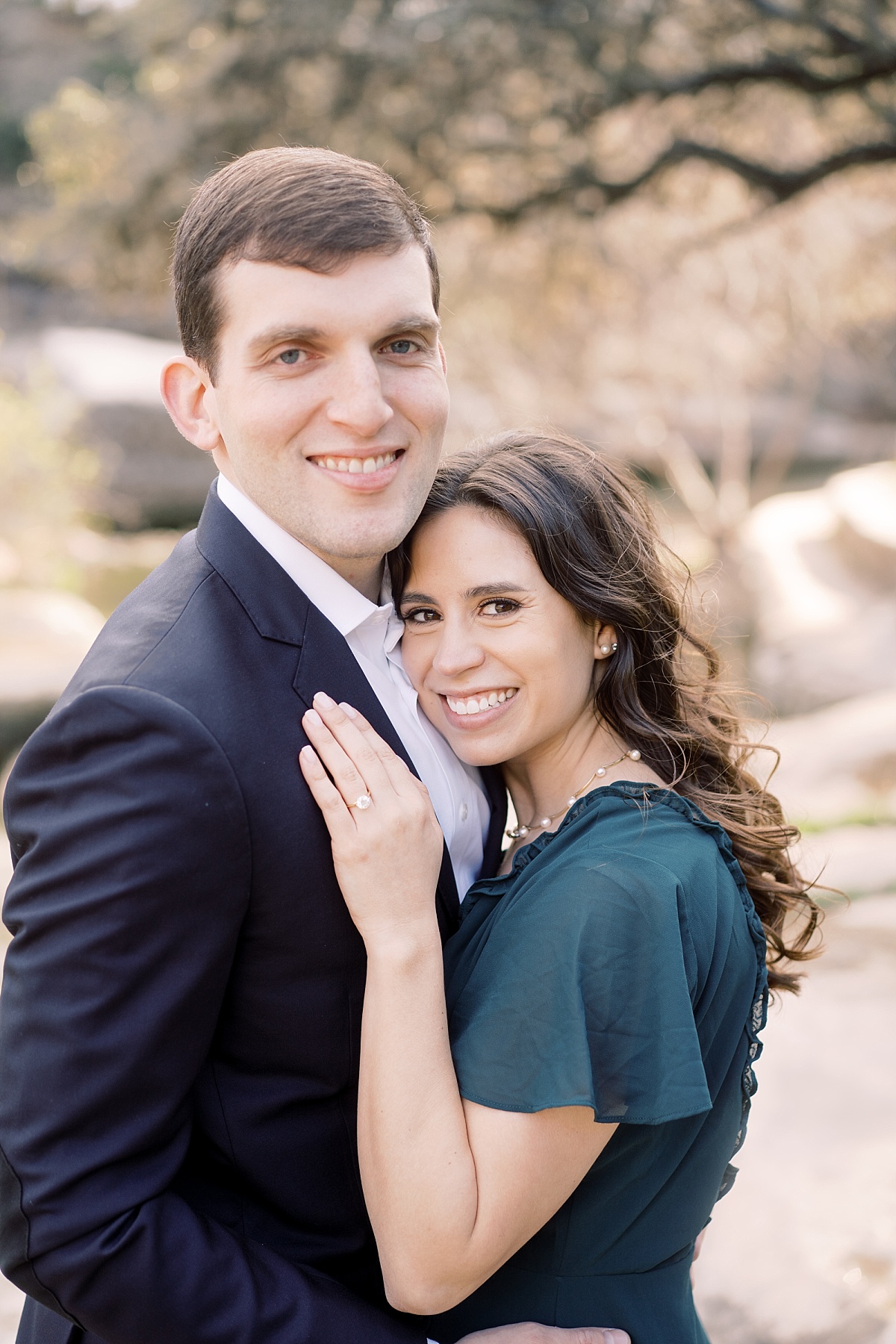 A beautiful woman with brown hair rests her cheek and hand on her fiance's chest during an engagement shoot in Texas.