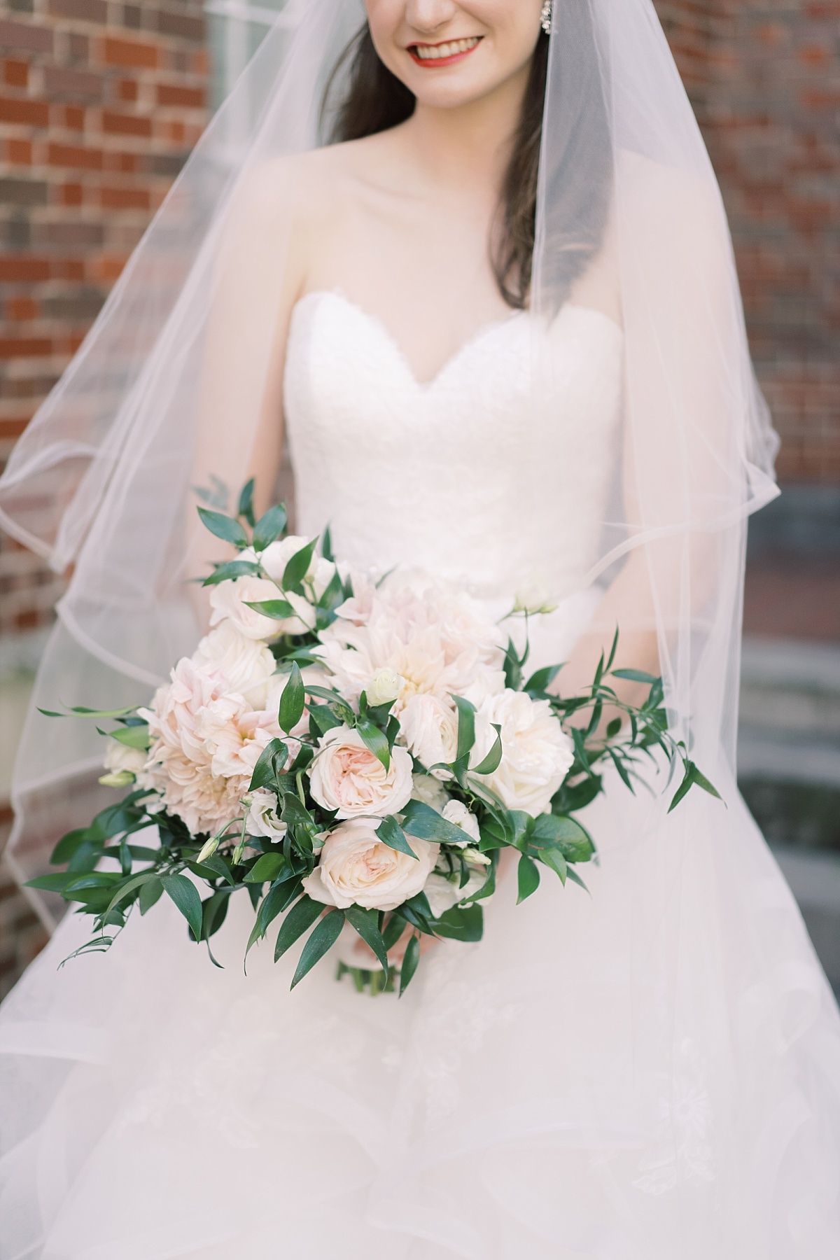 Close up of a smiling Caucasian bride holding a beautiful blush pink and green bouquet in Austin, Texas. Paige Vaughn Photography.