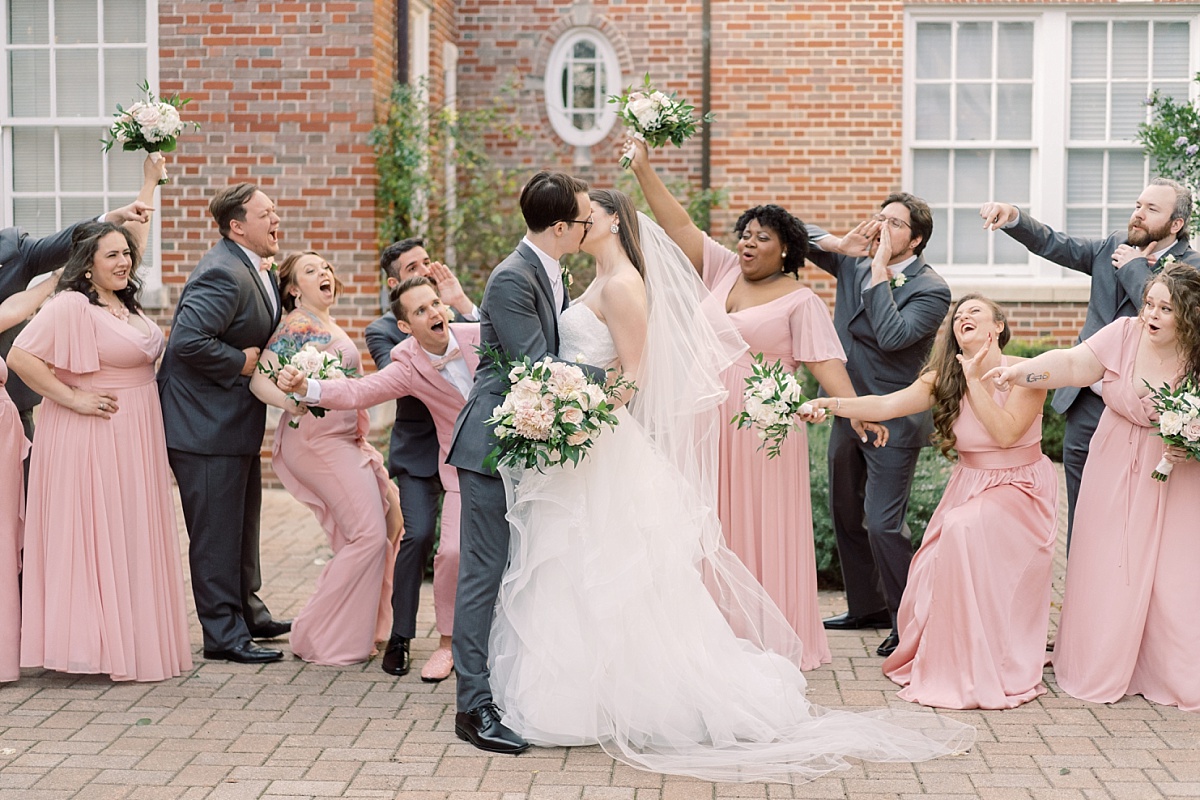 A wedding party cheering as the newlywed bride and groom kiss in front of The Mansion in Austin, Texas for wedding photographs by Paige Vaughn.