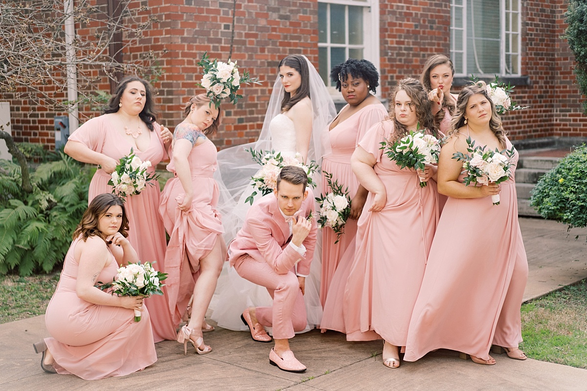 Beautiful Caucasian bride strikes a sassy, fun pose with her bridal party in Austin, Texas while being photographed by Paige Vaughn.