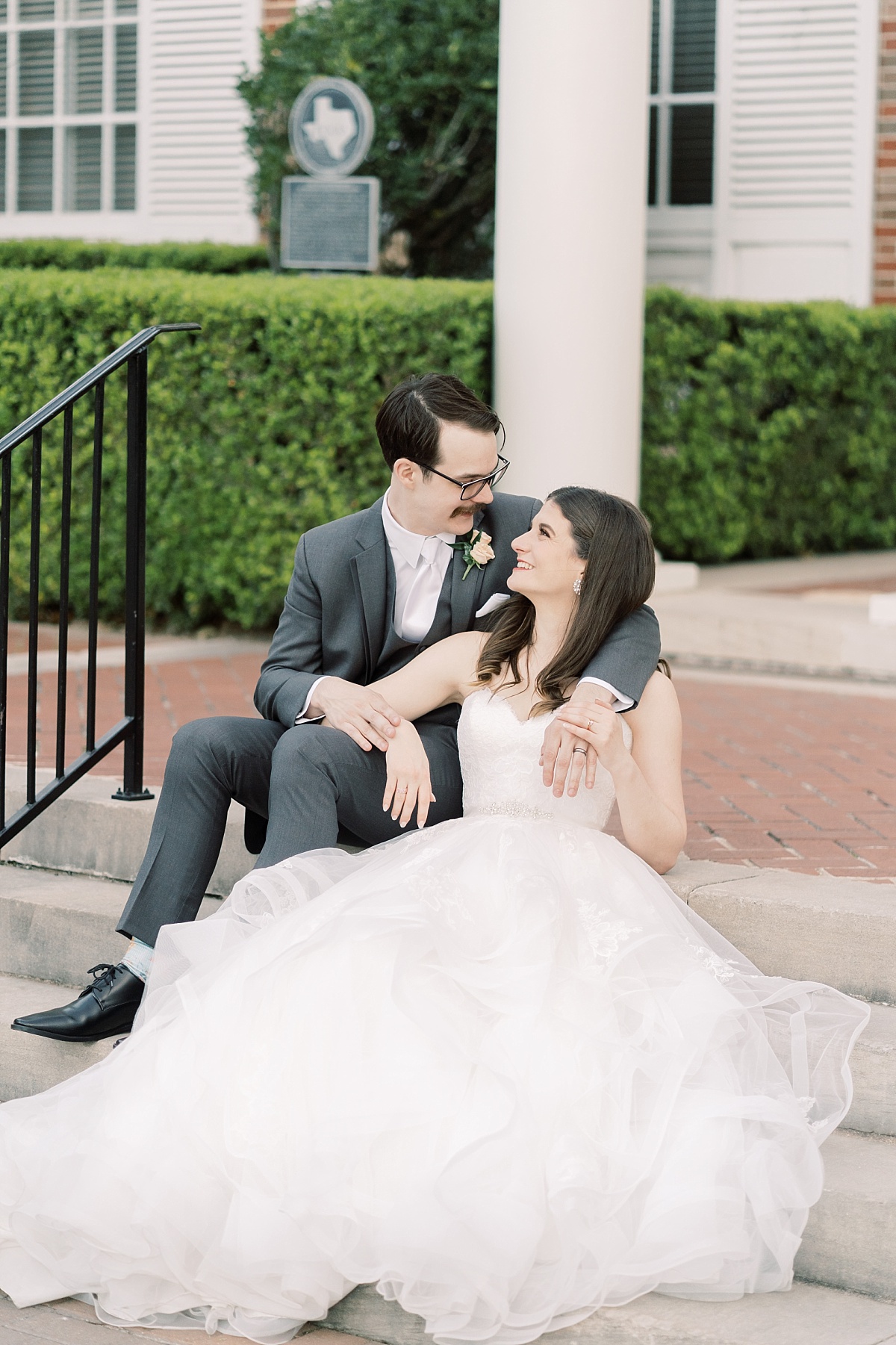 A happy, newlywed couple poses on the steps of TFWC Mansion for wedding photos in Austin, Texas with Paige Vaughn Photography.