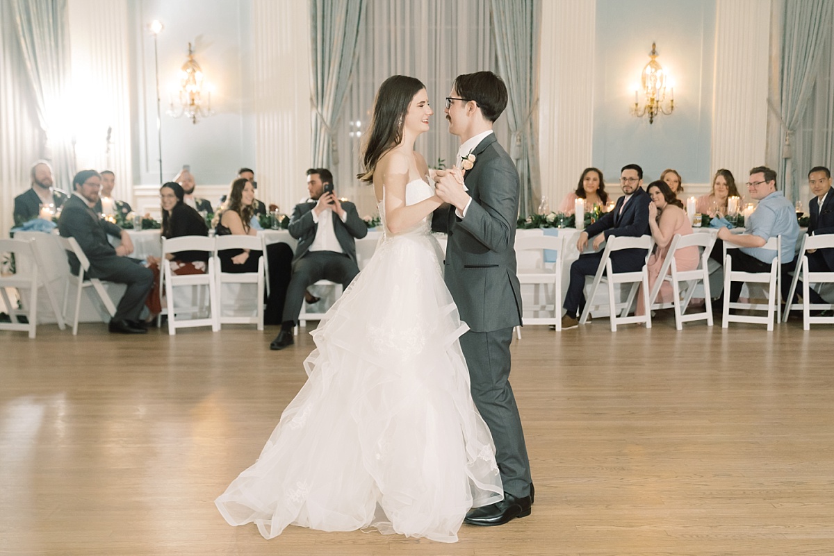 A Caucasian bride and groom have their first dance in front of family and friends while being captured by wedding photographer in Austin, Texas.