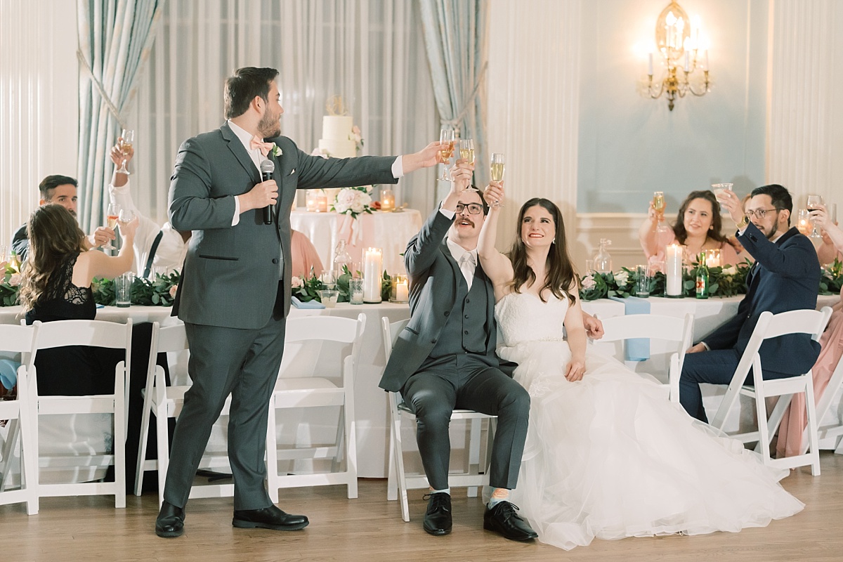 A groomsman offers a toast to the bride and groom at their southern wedding at The Mansion in Austin, Texas while the moment is captured by a wedding photographer.