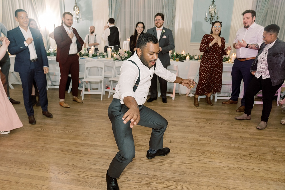 A wedding party guest dances while other guests cheer him on at The Mansion, Austin, Texas.