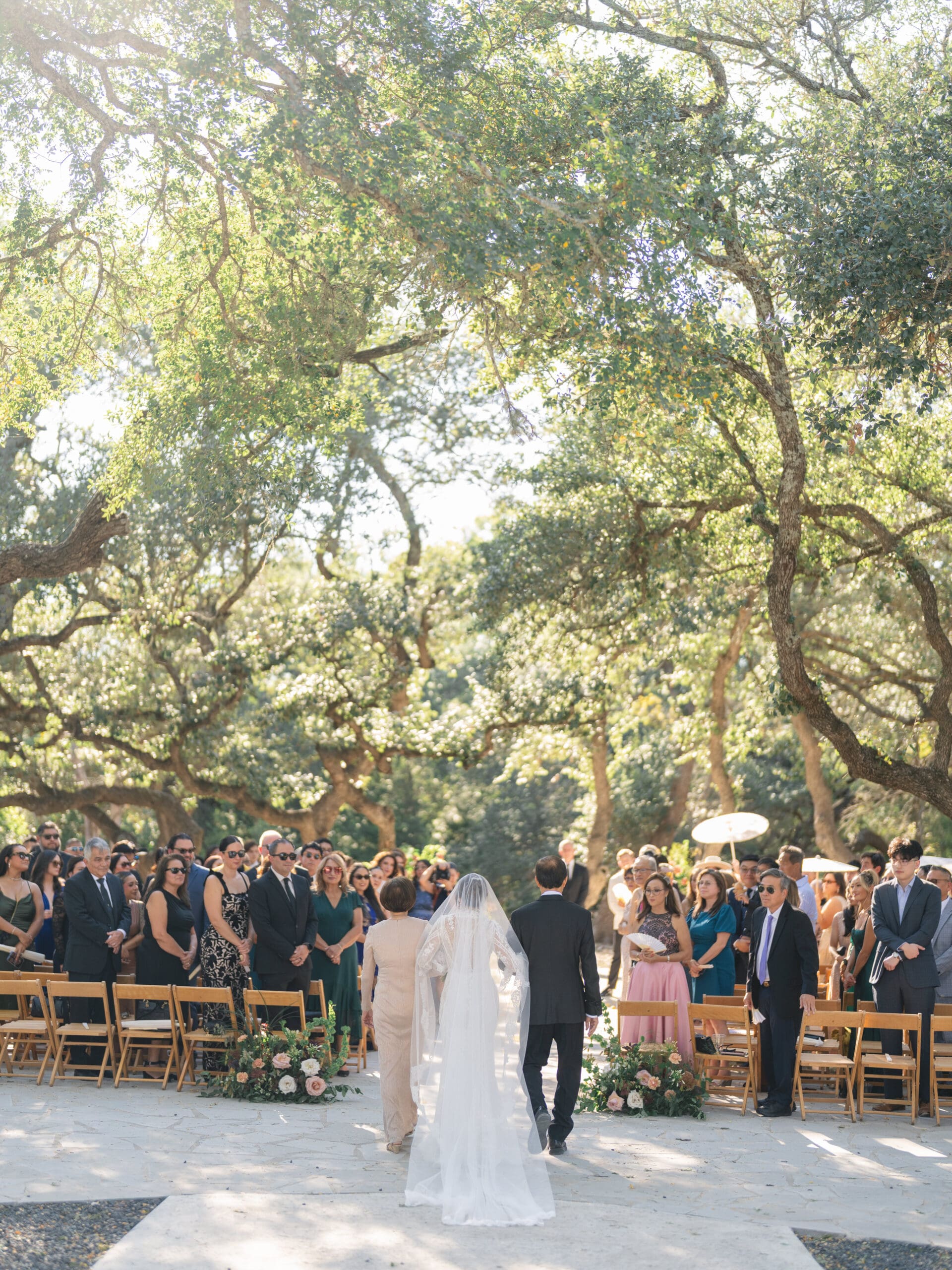 Outdoor ceremony at The Addison Grove with guests seated beneath twinkling lights and oak trees