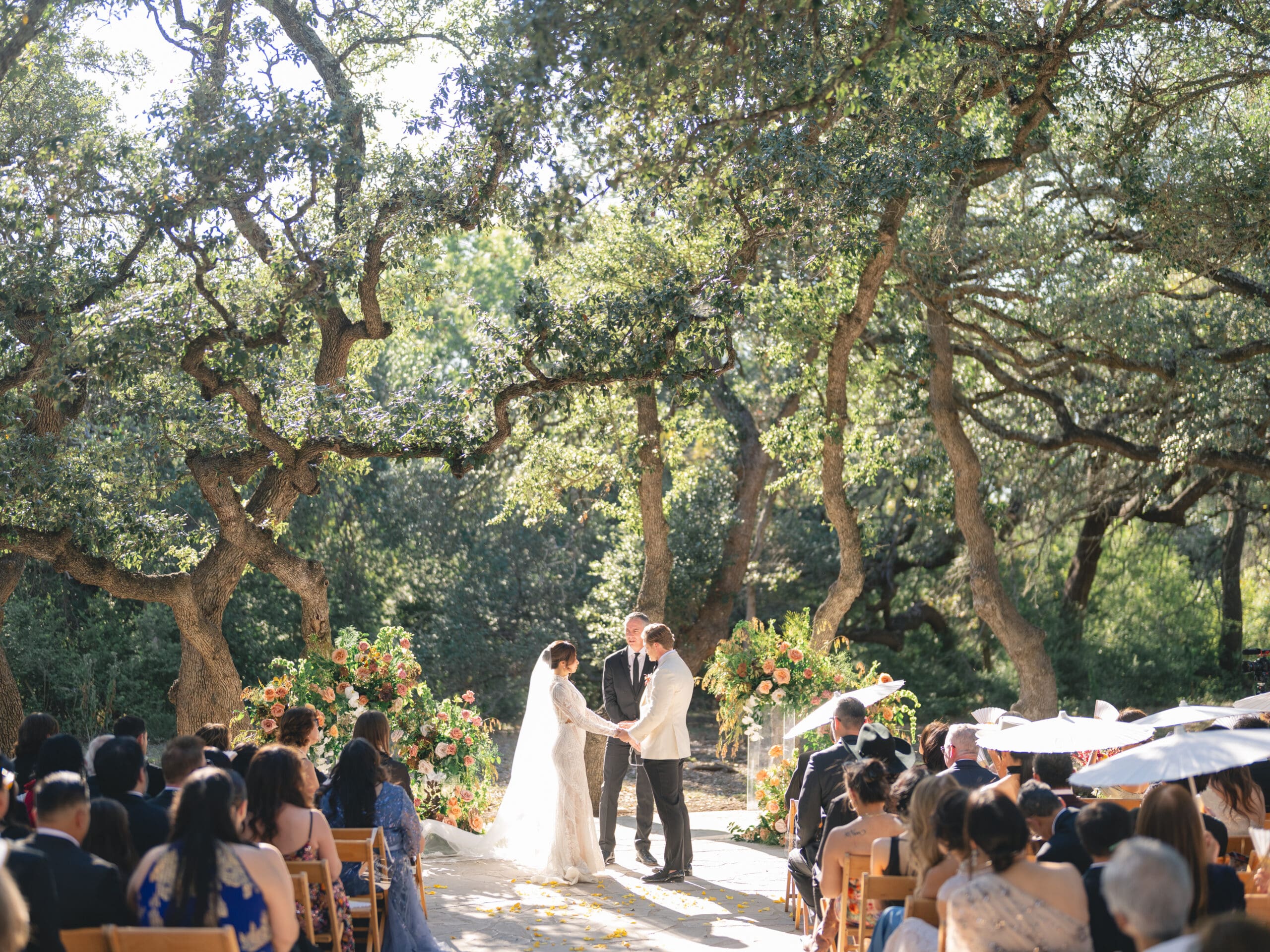 Outdoor ceremony at The Addison Grove with guests seated beneath twinkling lights and oak trees