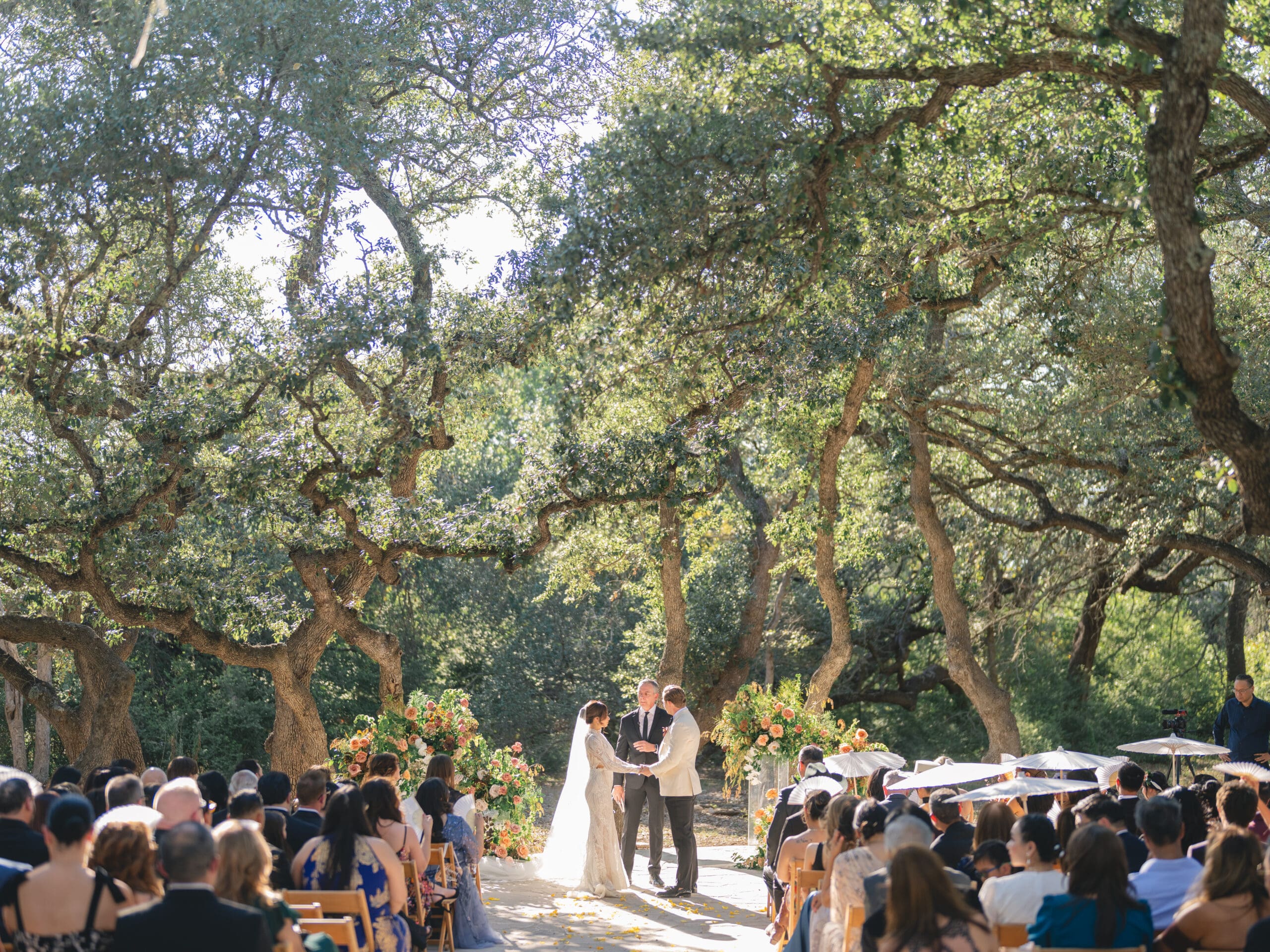 Outdoor ceremony at The Addison Grove with guests seated beneath twinkling lights and oak trees
