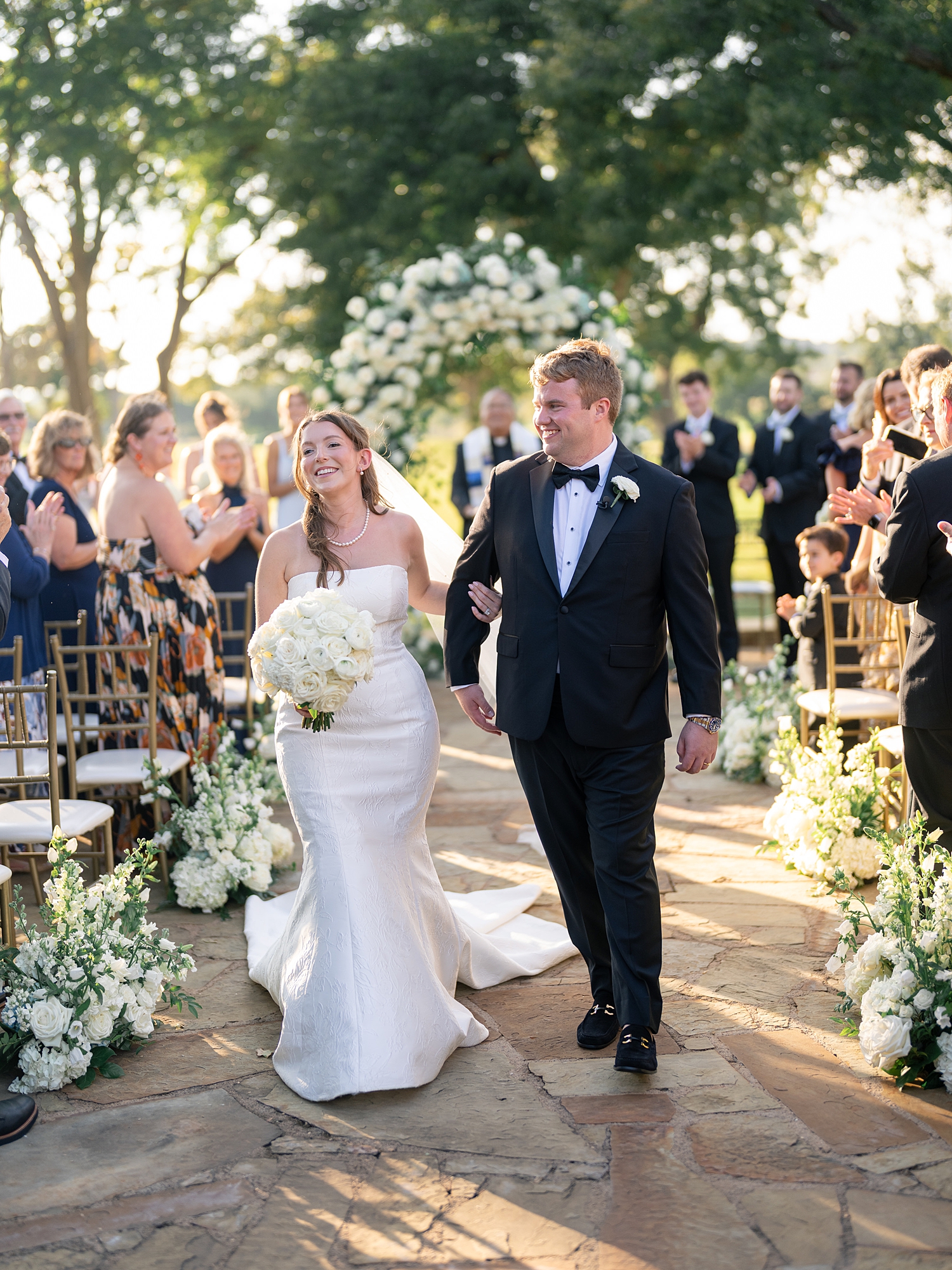 Outdoor ceremony moment at Escondido Golf Club with guests seated and floral arch backdrop