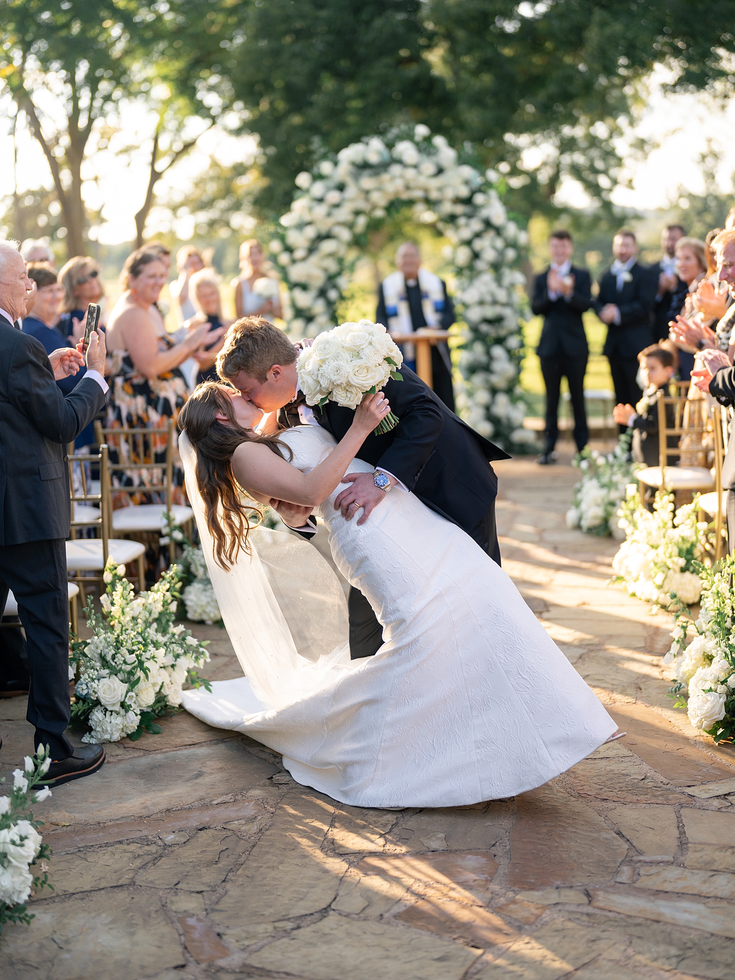 Outdoor ceremony moment at Escondido Golf Club with guests seated and floral arch backdrop