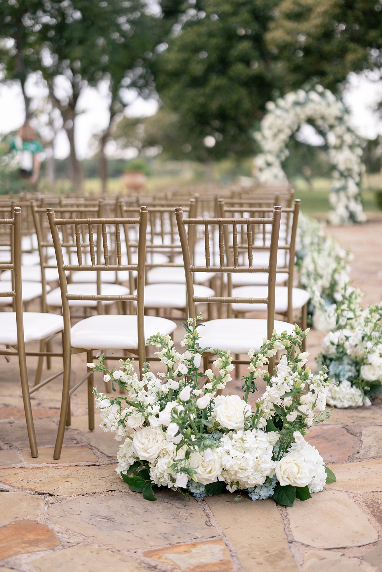 Outdoor ceremony moment at Escondido Golf Club with guests seated and floral arch backdrop
