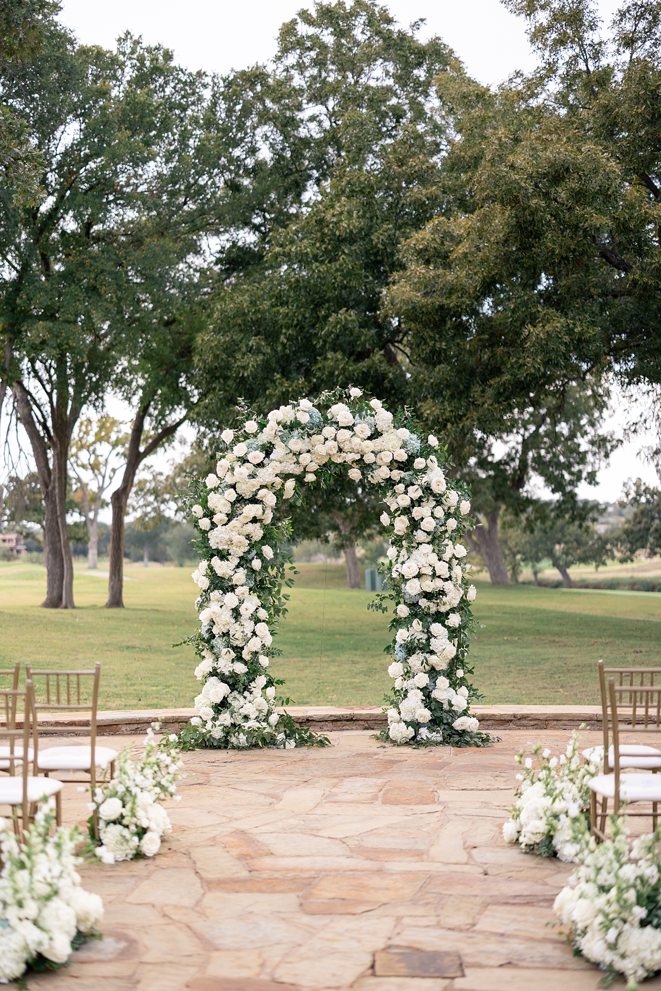 Outdoor ceremony moment at Escondido Golf Club with guests seated and floral arch backdrop