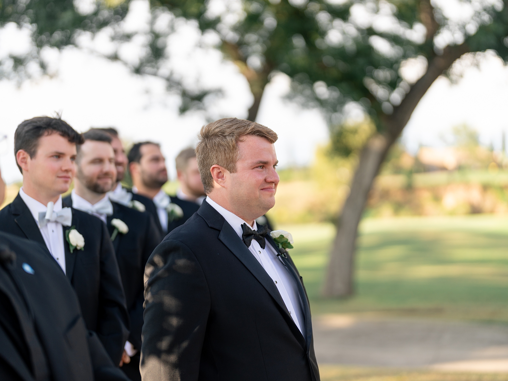 Outdoor ceremony moment at Escondido Golf Club with guests seated and floral arch backdrop
