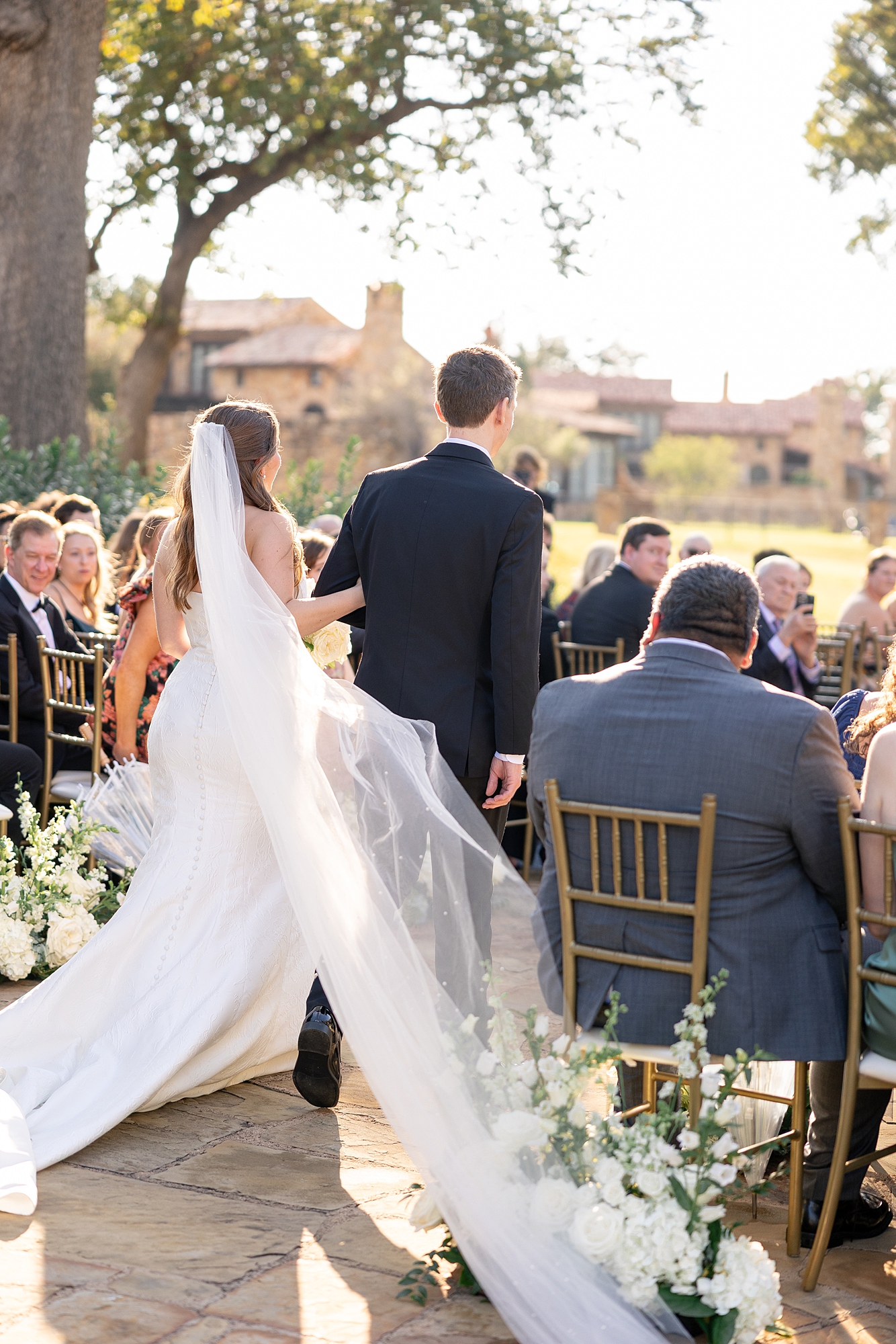 Outdoor ceremony moment at Escondido Golf Club with guests seated and floral arch backdrop