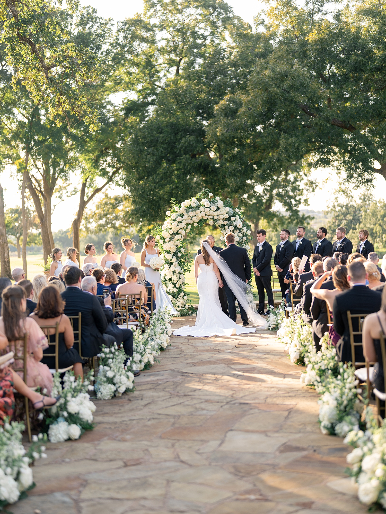 Outdoor ceremony moment at Escondido Golf Club with guests seated and floral arch backdrop