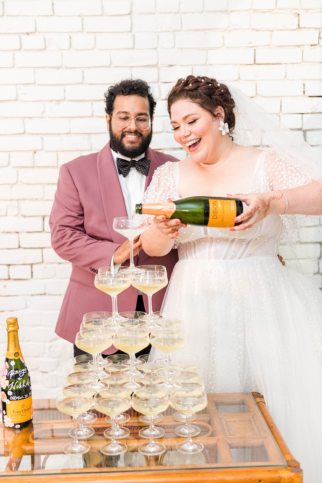 Joyful portrait of bride and groom mid-celebration at their fall wedding weekend in Texas, champagne tower