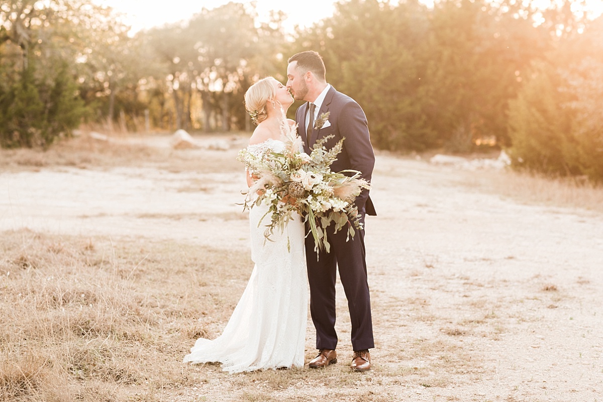 A gorgeous bride with a stunning bouquet and handsome groom kiss at their wedding while posing for wedding photos with Paige Vaughn Photogrpahy