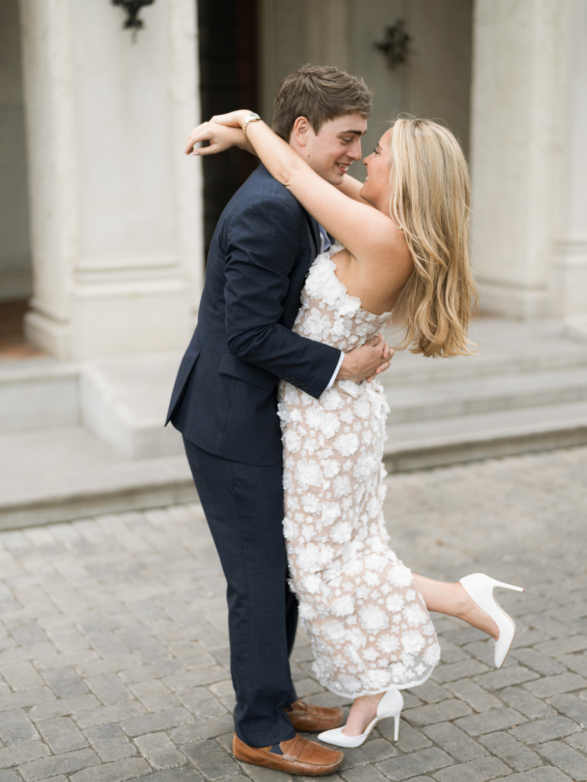 Engaged couple walking through the elegant gardens of Commodore Perry Estate, captured on film with soft natural light and classic architecture in the background