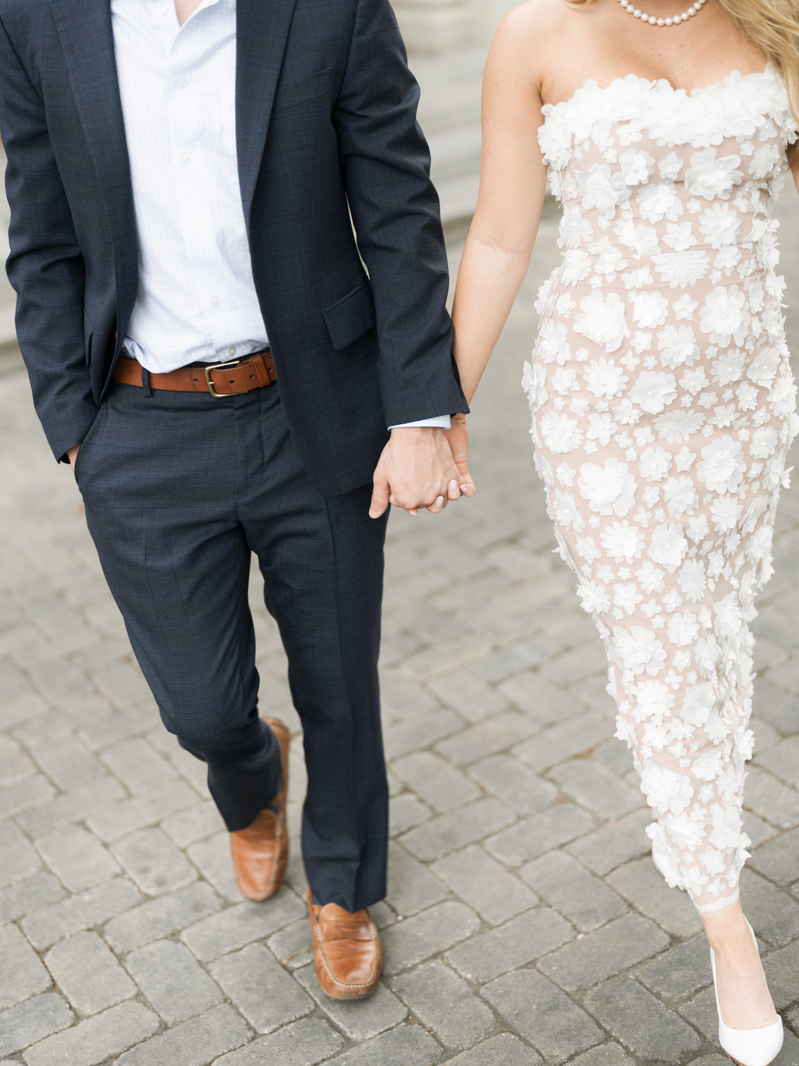 Engaged couple walking through the elegant gardens of Commodore Perry Estate, captured on film with soft natural light and classic architecture in the background