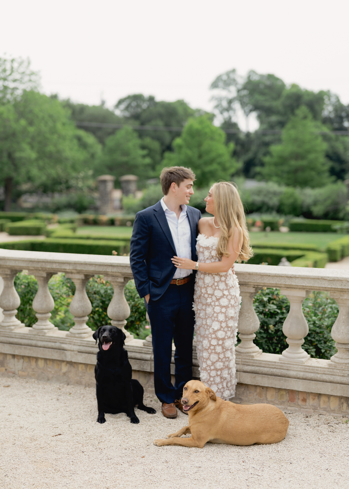 Engagement photo of couple cuddling with their pups on the lawn of Commodore Perry Estate