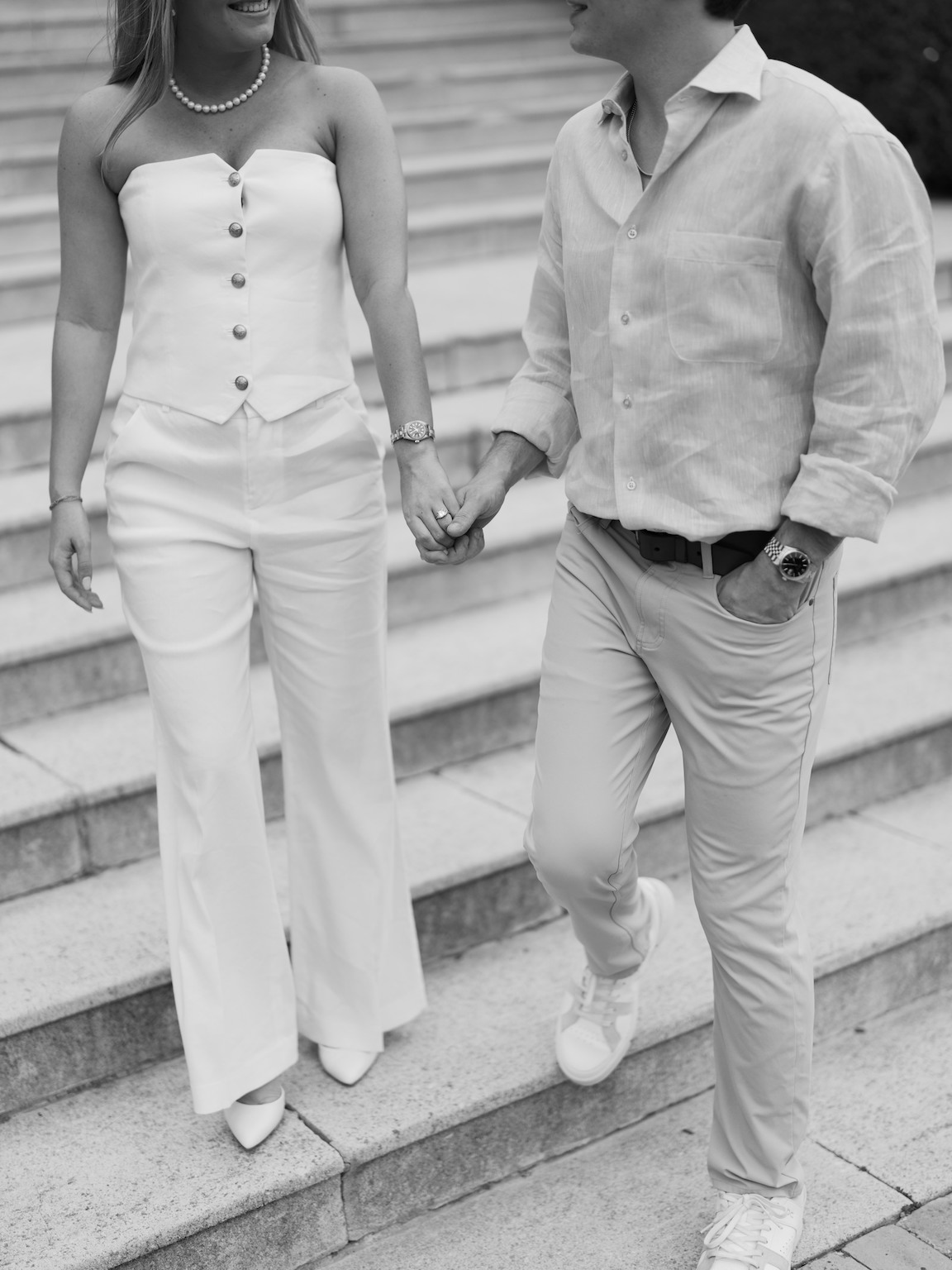 Engaged couple walking through the elegant gardens of Commodore Perry Estate, captured on film with soft natural light and classic architecture in the background