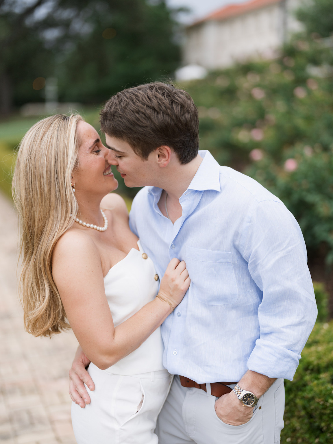 Engaged couple walking through the elegant gardens of Commodore Perry Estate, captured on film with soft natural light and classic architecture in the background