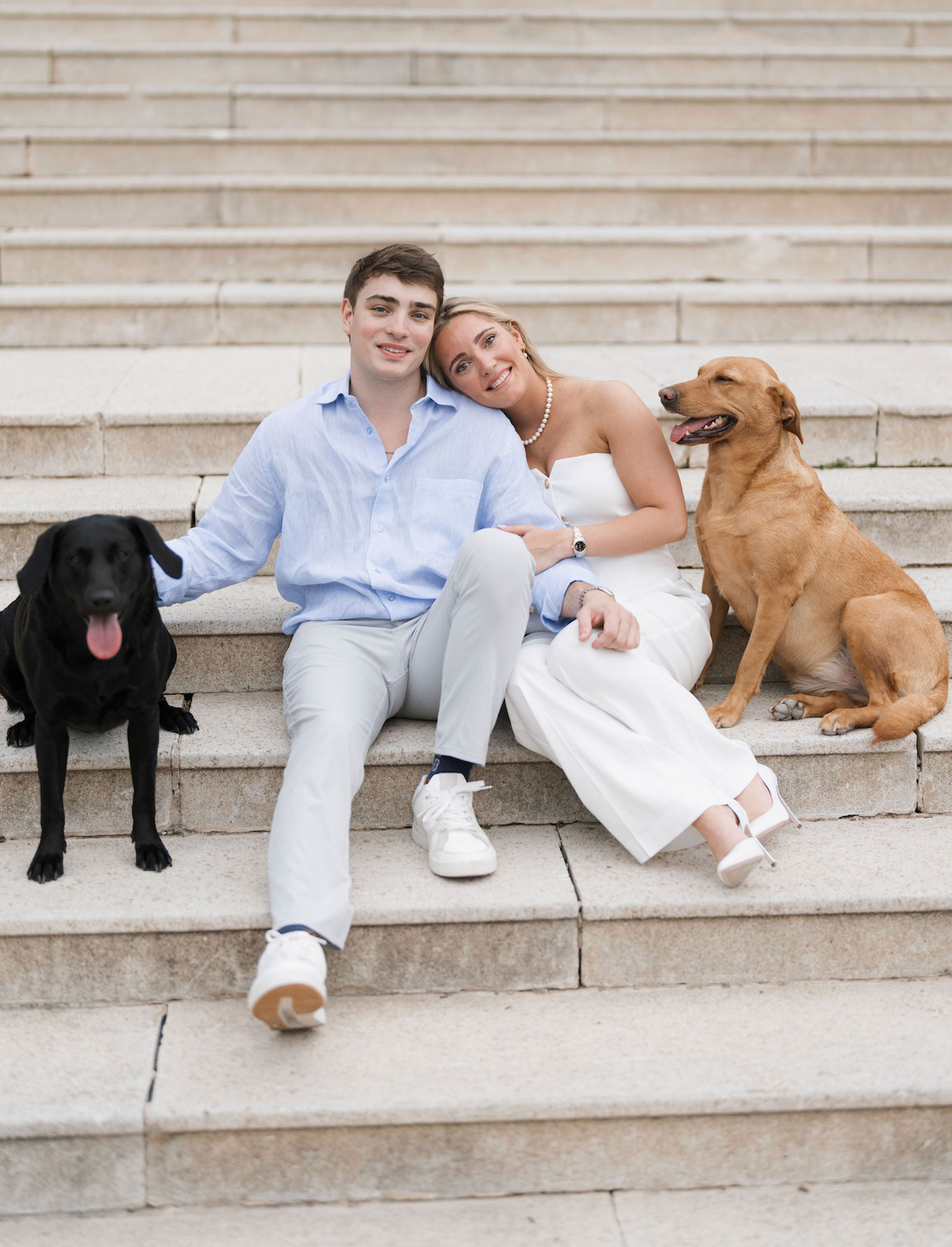 Engagement photo of couple cuddling with their dogs on the lawn of Commodore Perry Estate
