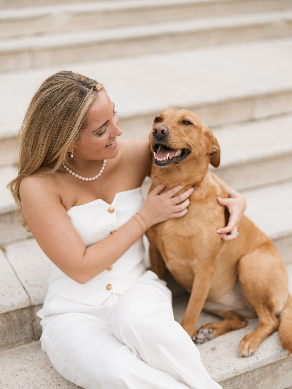 Engagement photo of couple cuddling with their dogs on the lawn of Commodore Perry Estate