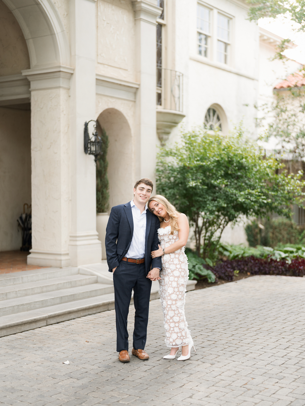 Engaged couple walking through the elegant gardens of Commodore Perry Estate, captured on film with soft natural light and classic architecture in the background