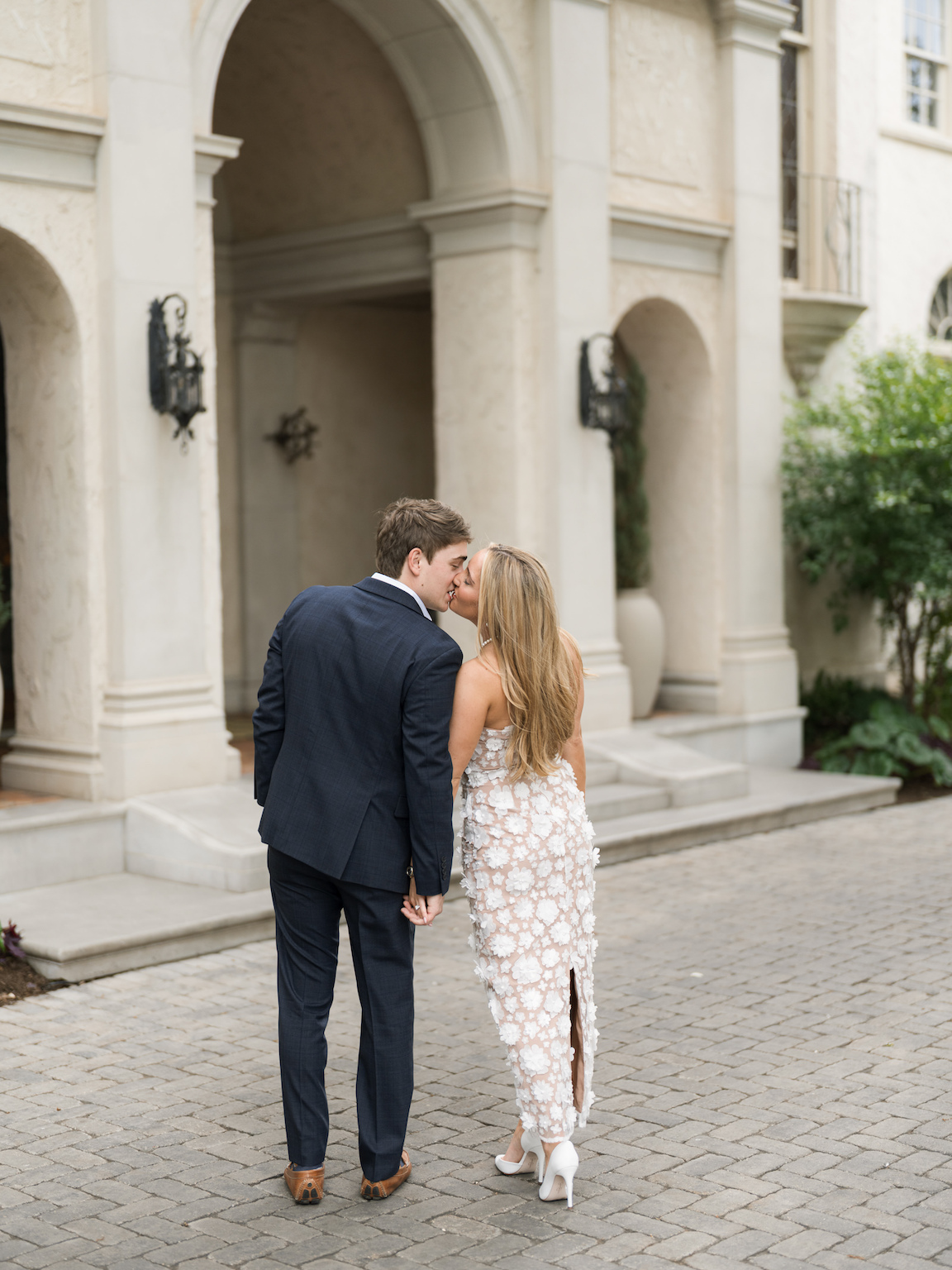 Engaged couple walking through the elegant gardens of Commodore Perry Estate, captured on film with soft natural light and classic architecture in the background