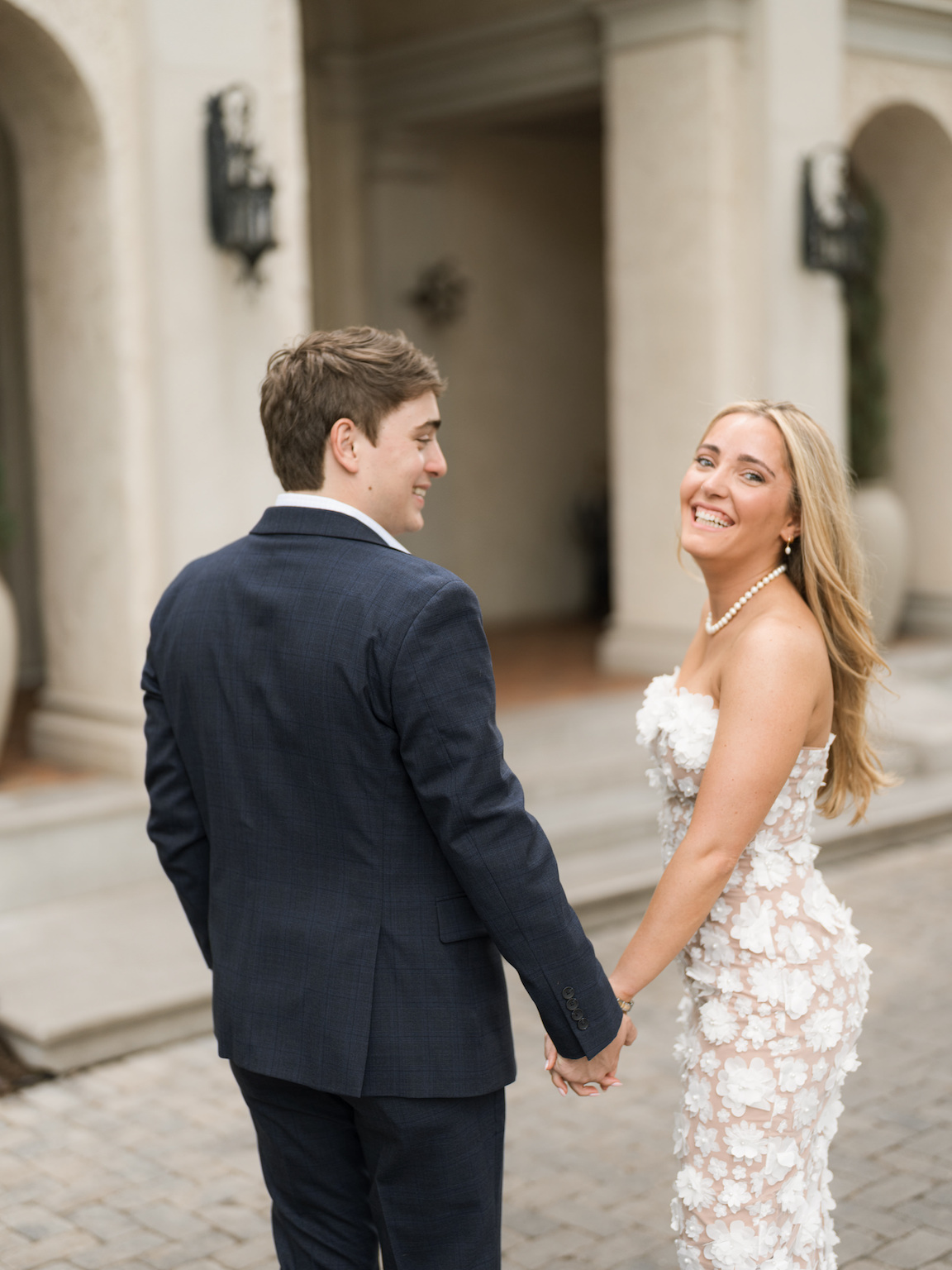Engaged couple walking through the elegant gardens of Commodore Perry Estate, captured on film with soft natural light and classic architecture in the background