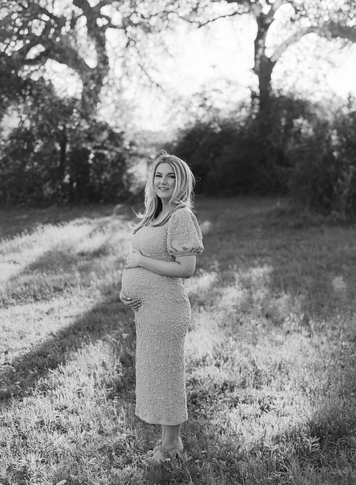 Expecting mother in a grassy field, photographed on film with glowing natural light