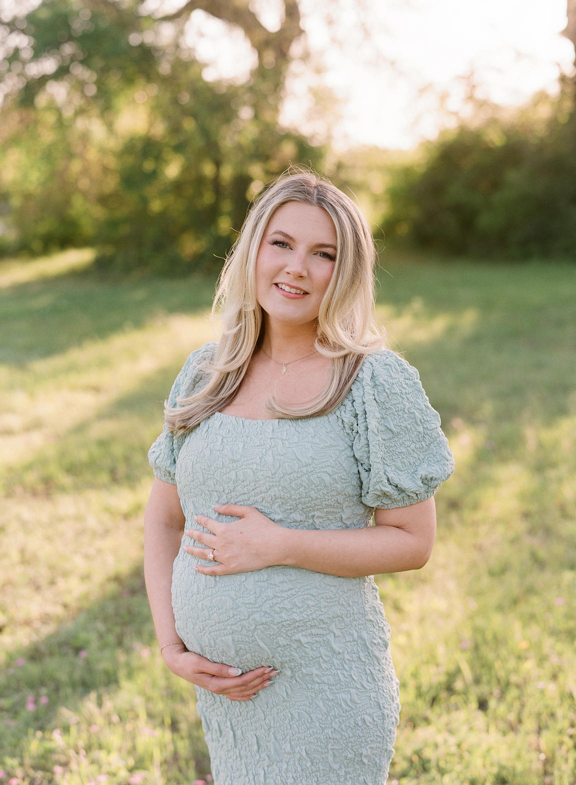 Expecting mother in a grassy field, photographed on film with glowing natural light