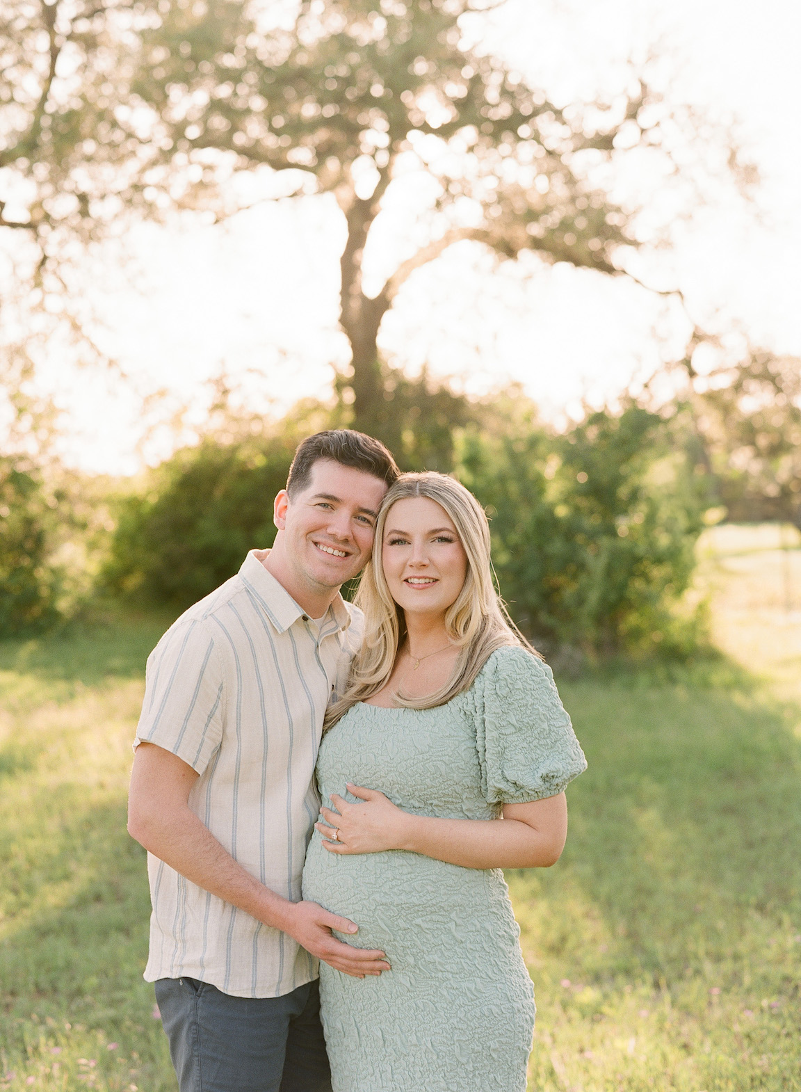 Expecting mother in a grassy field, photographed on film with glowing natural light