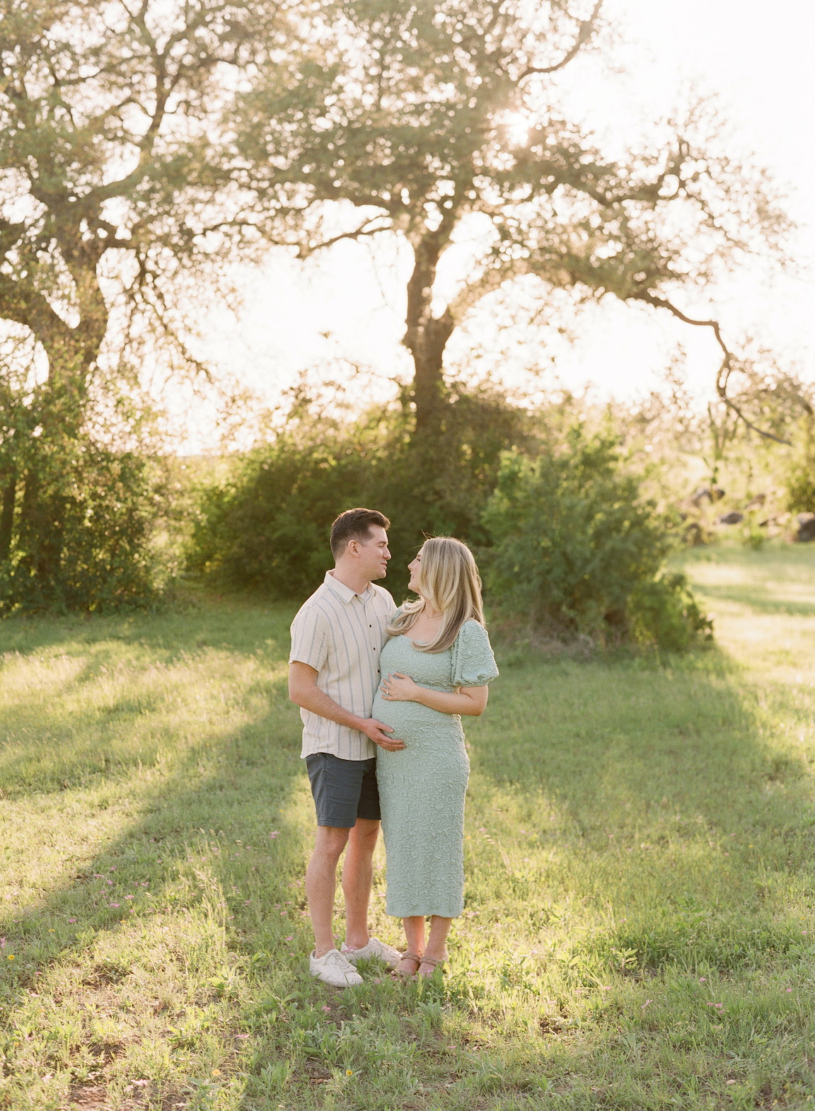 Expecting mother in a grassy field, photographed on film with glowing natural light