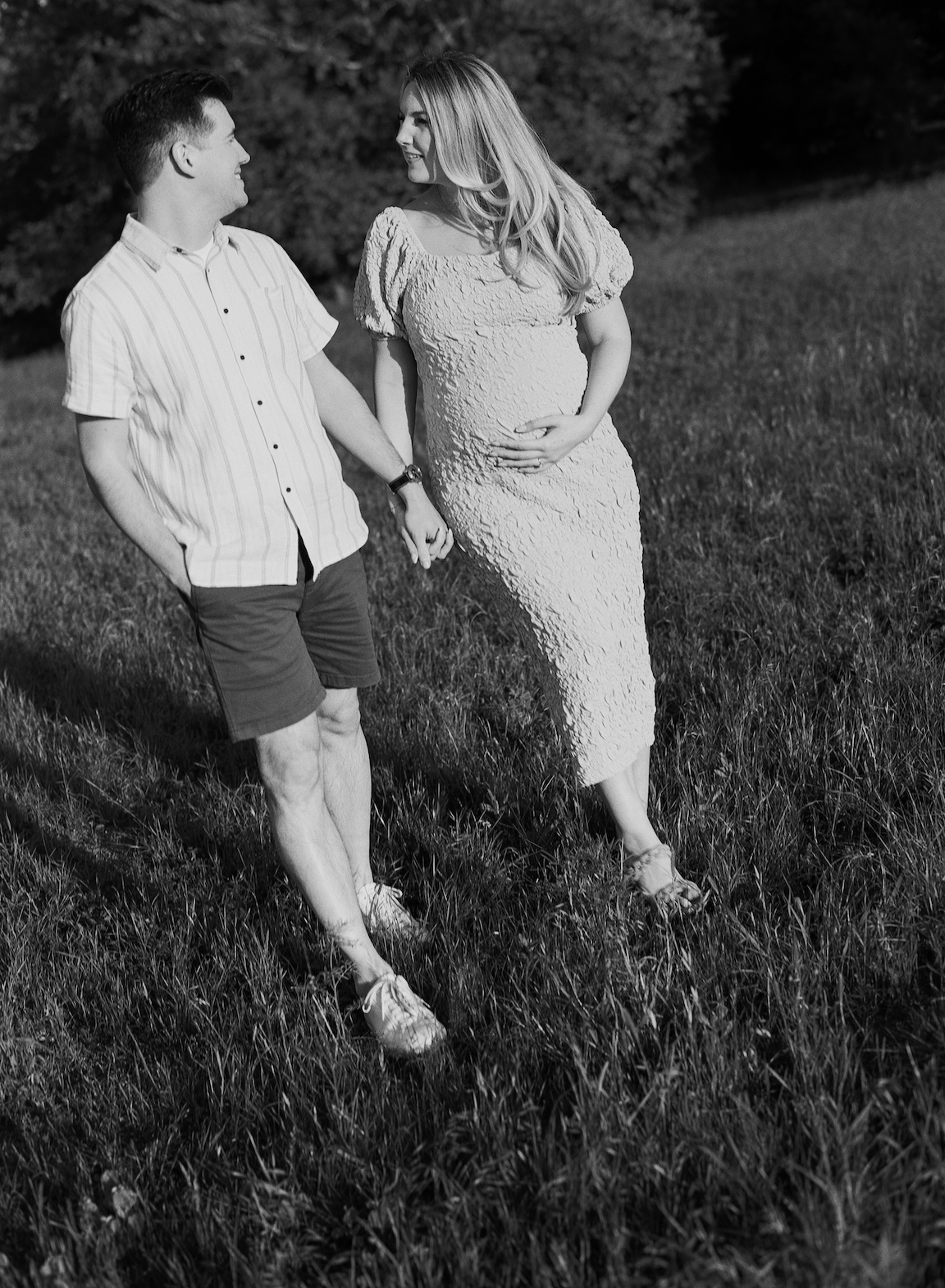 Chelsea and Clayton during their film maternity photos in a sun-drenched Austin park, surrounded by greenery