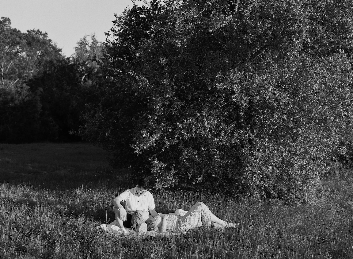 Chelsea and Clayton during their film maternity photos in a sun-drenched Austin park, surrounded by greenery
