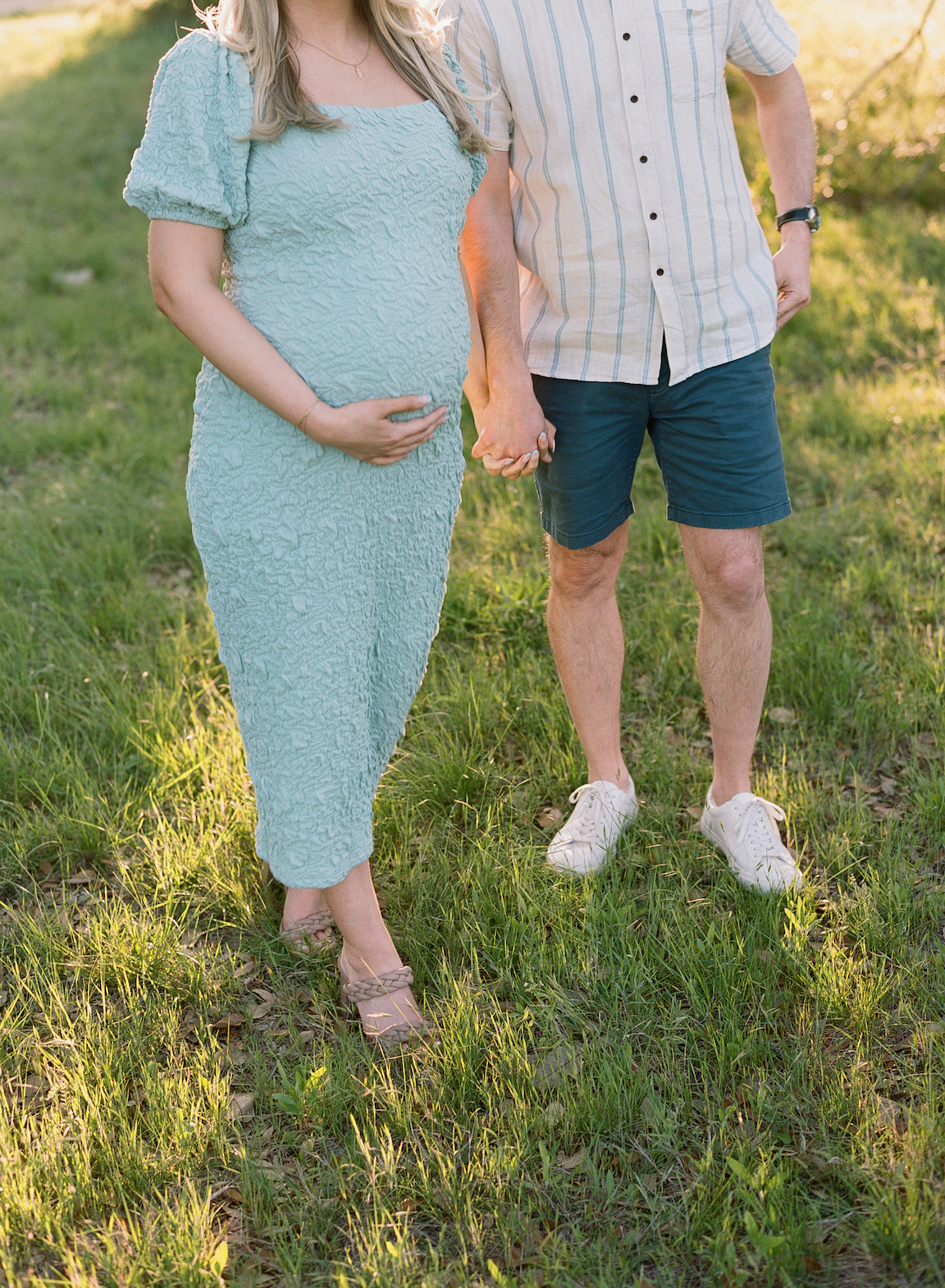 Chelsea and Clayton during their film maternity photos in a sun-drenched Austin park, surrounded by greenery