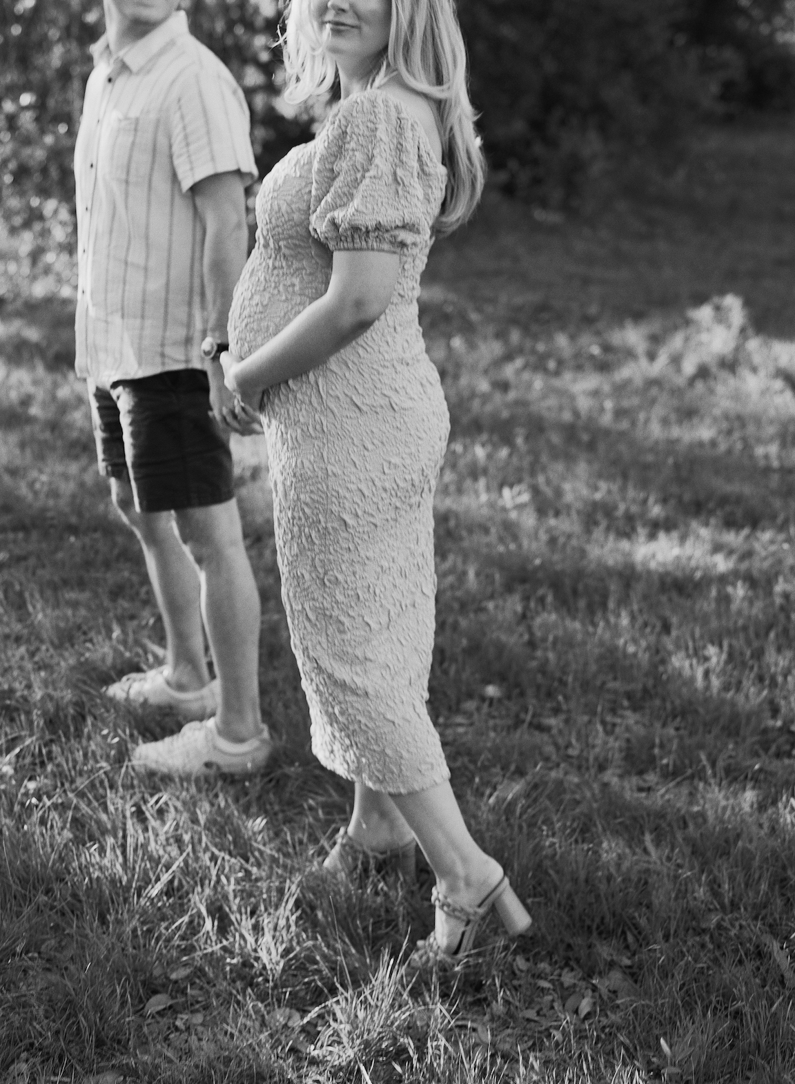 Chelsea and Clayton during their film maternity photos in a sun-drenched Austin park, surrounded by greenery