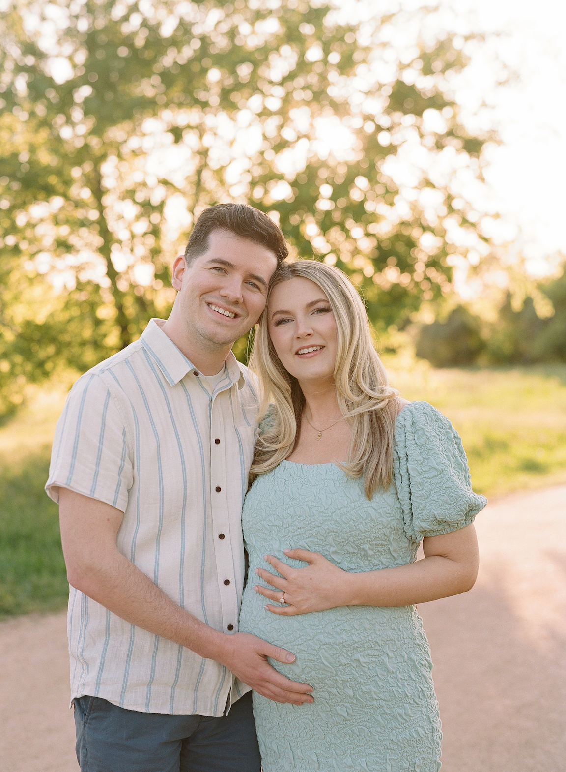 Chelsea and Clayton during their film maternity photos in a sun-drenched Austin park, surrounded by greenery