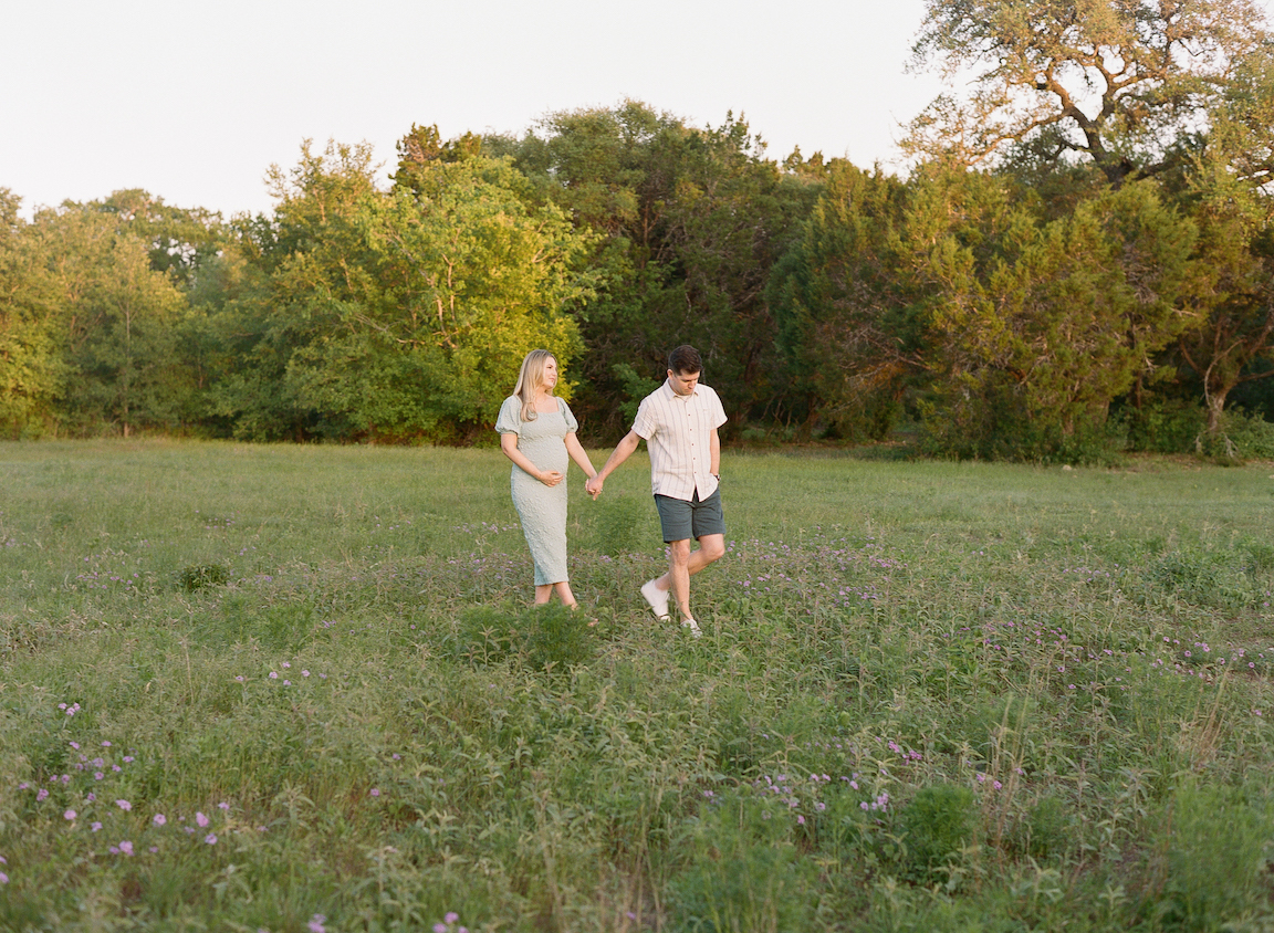 Chelsea and Clayton during their film maternity photos in a sun-drenched Austin park, surrounded by greenery