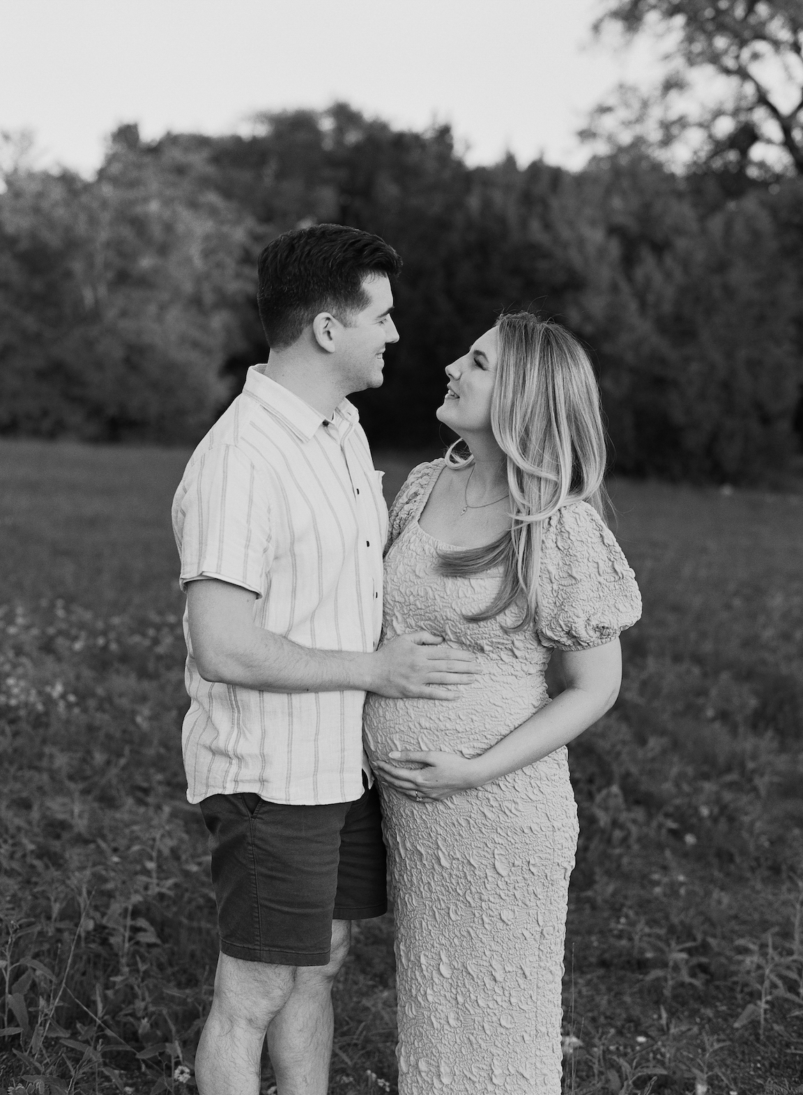 Chelsea and Clayton during their film maternity photos in a sun-drenched Austin park, surrounded by greenery