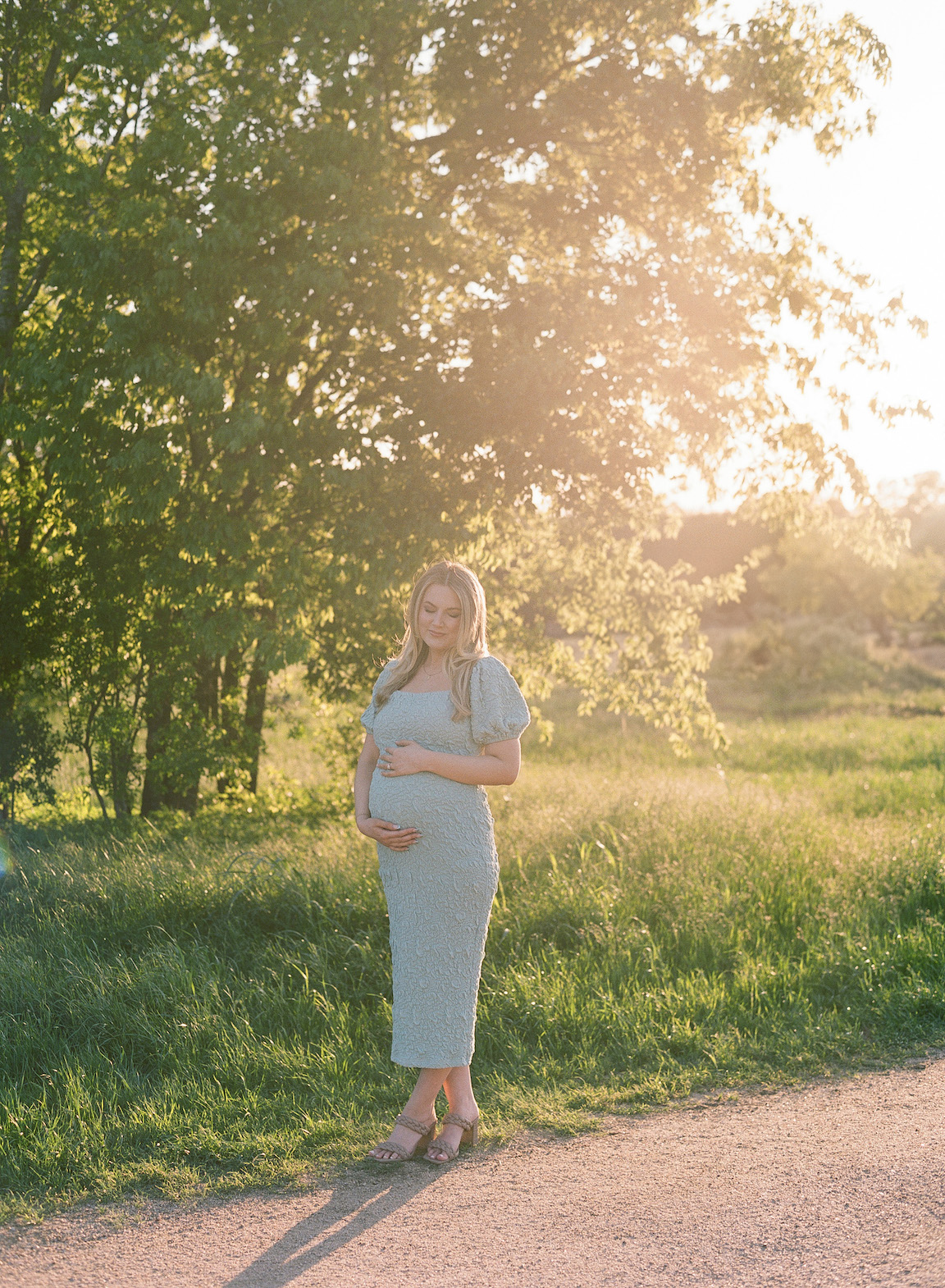 Expecting mother in a grassy field, photographed on film with glowing natural light
