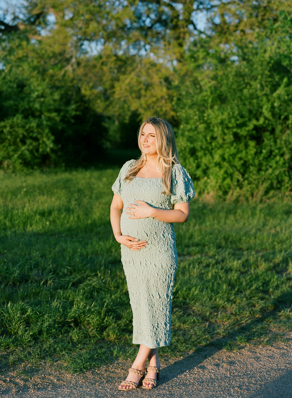Expecting mother in a grassy field, photographed on film with glowing natural light