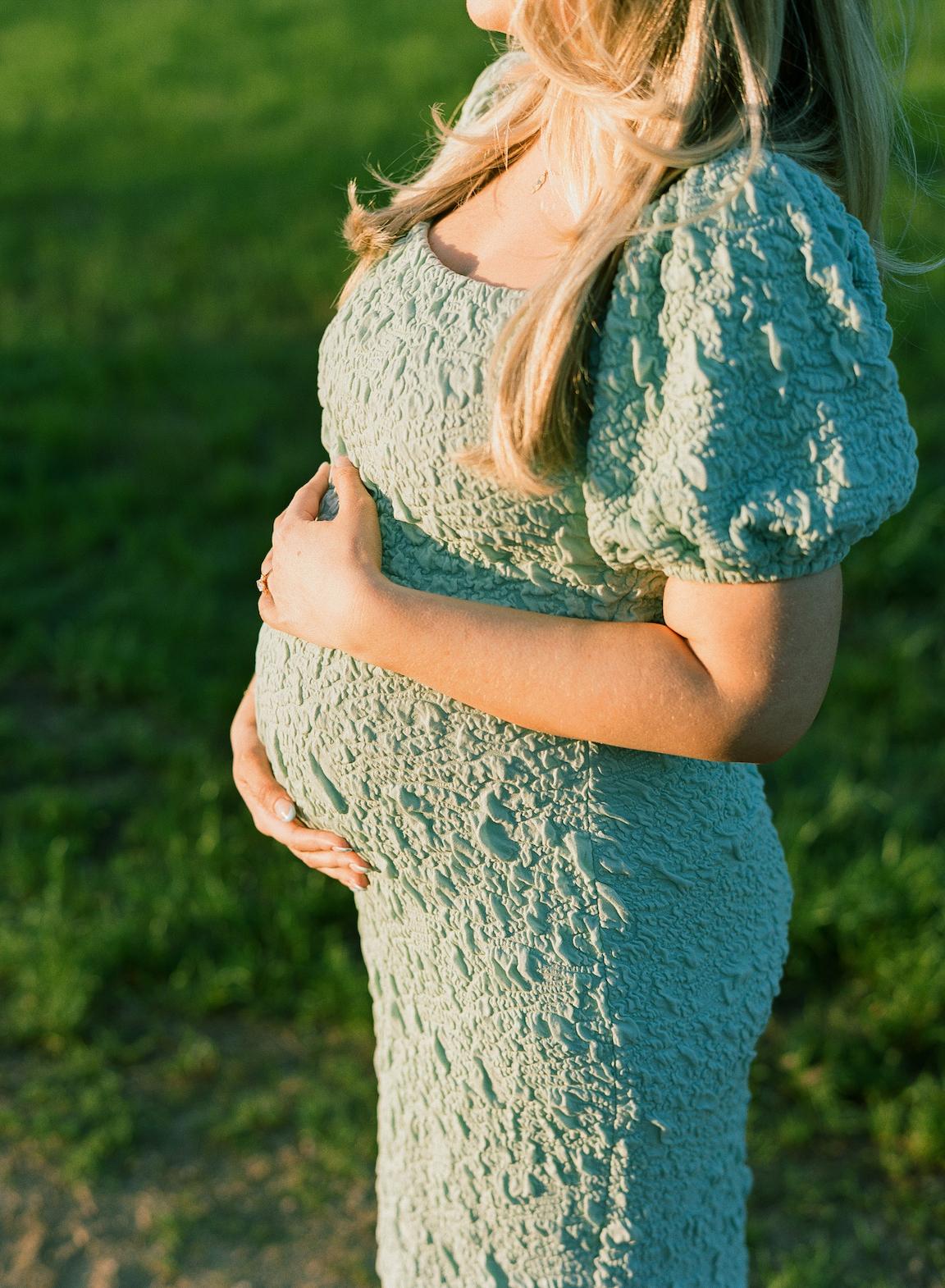 Expecting mother in a grassy field, photographed on film with glowing natural light