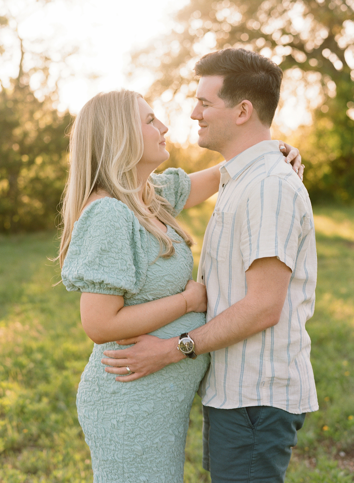 Chelsea and Clayton during their film maternity photos in a sun-drenched Austin park, surrounded by greenery