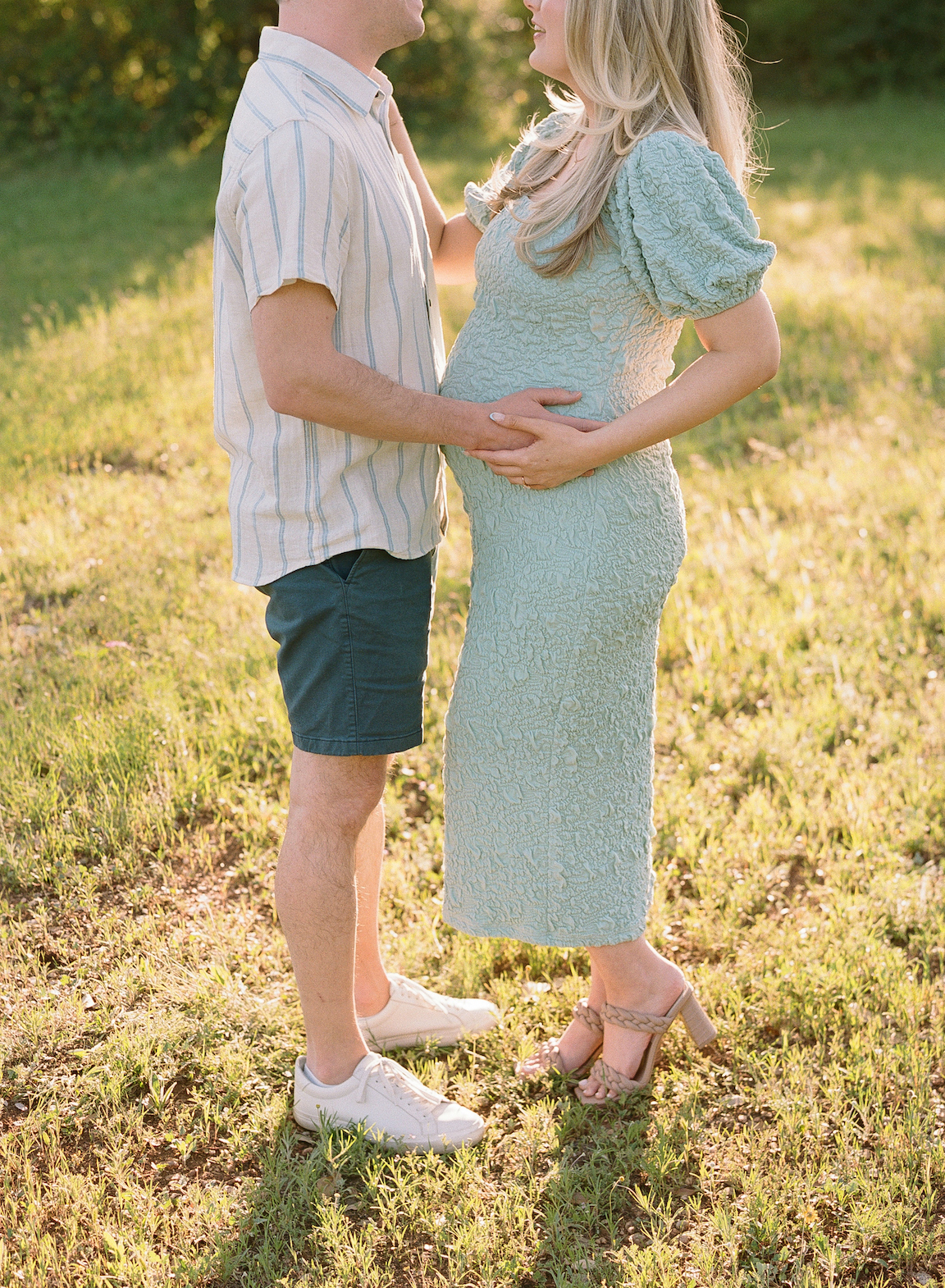 Chelsea and Clayton during their film maternity photos in a sun-drenched Austin park, surrounded by greenery