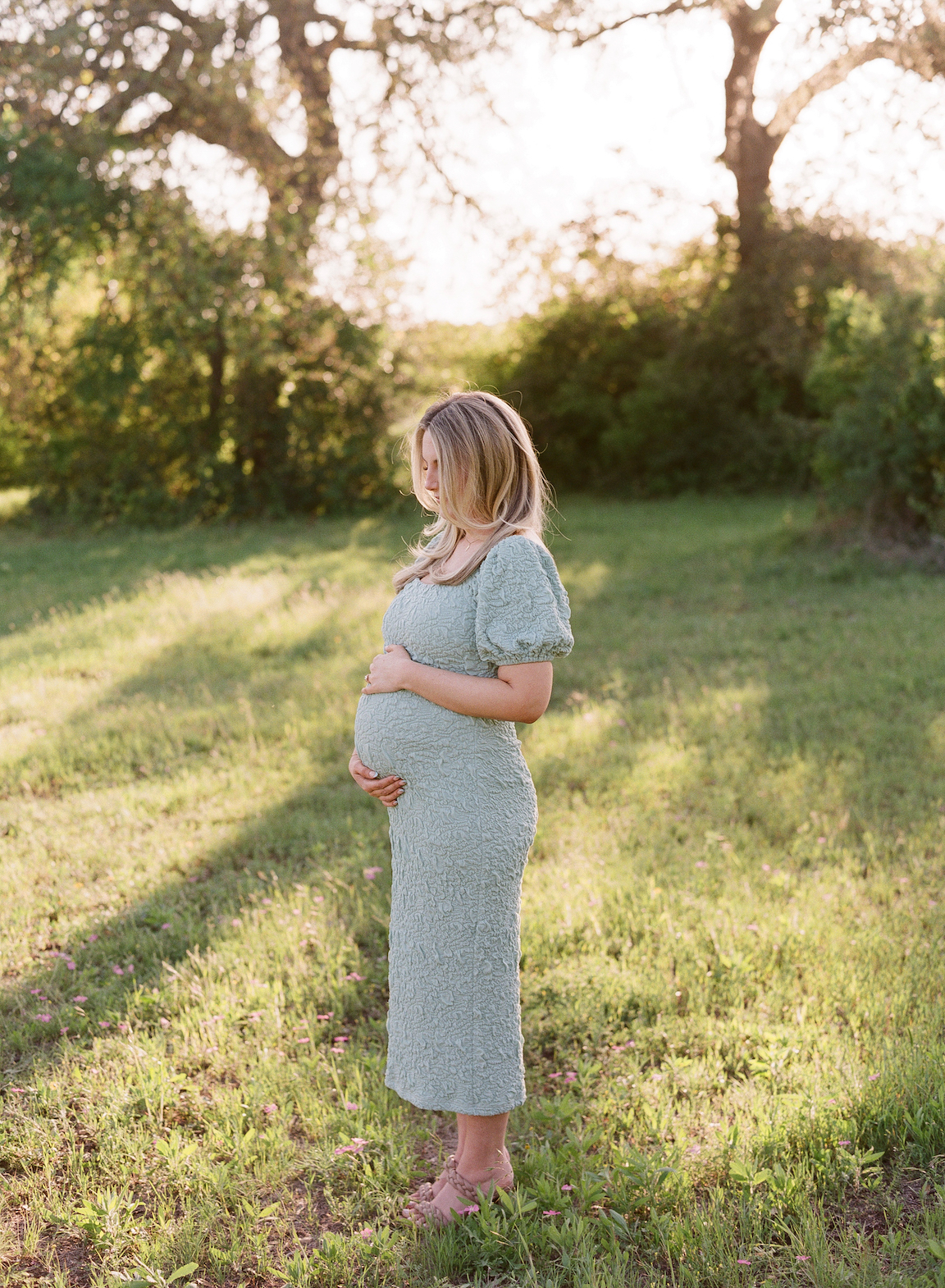 Expecting mother in a grassy field, photographed on film with glowing natural light